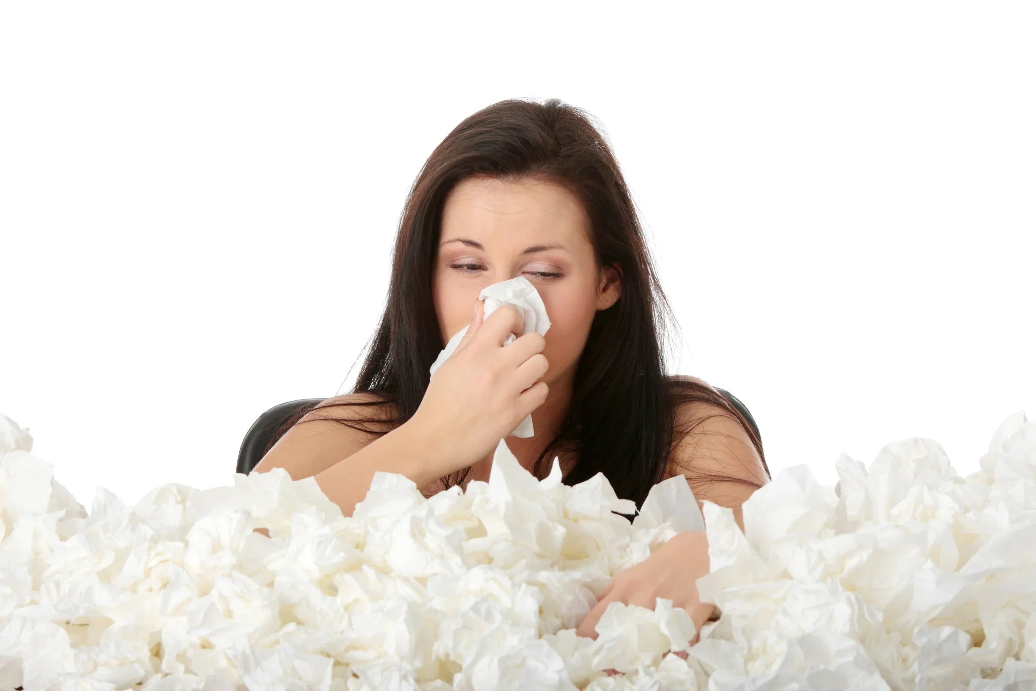 Woman with tissue surrounded by tissues, showing allergy or sensitive skin symptoms.