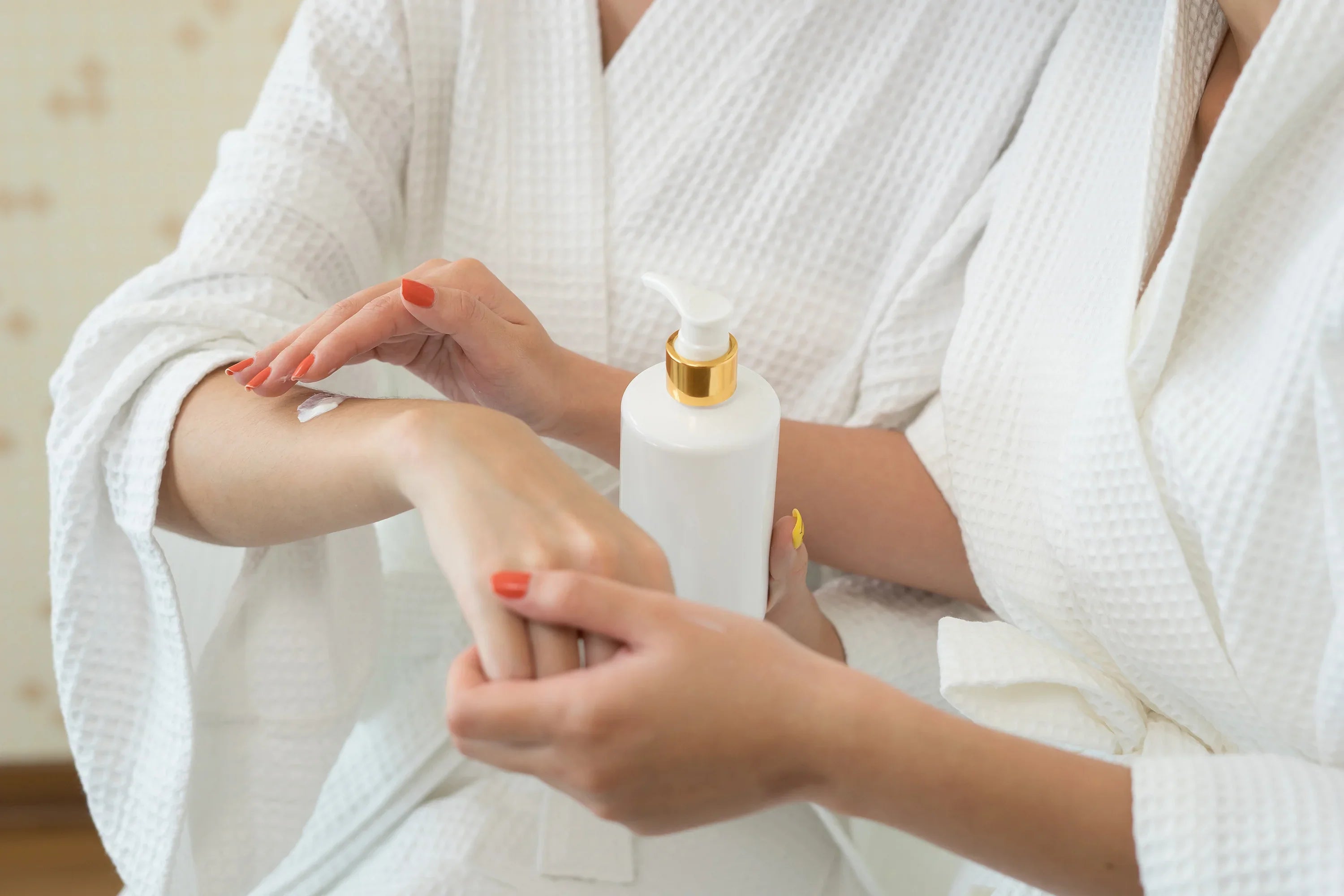 Women in white cotton robes applying hypoallergenic lotion to arm, allergy-free skincare