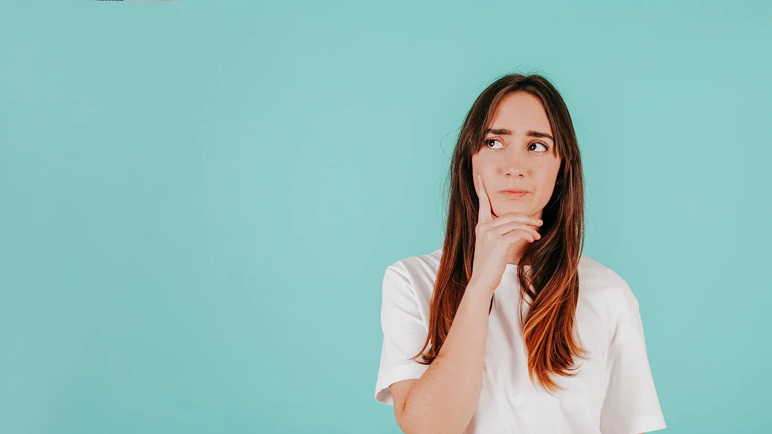 Woman in white organic cotton shirt thinking against light blue background