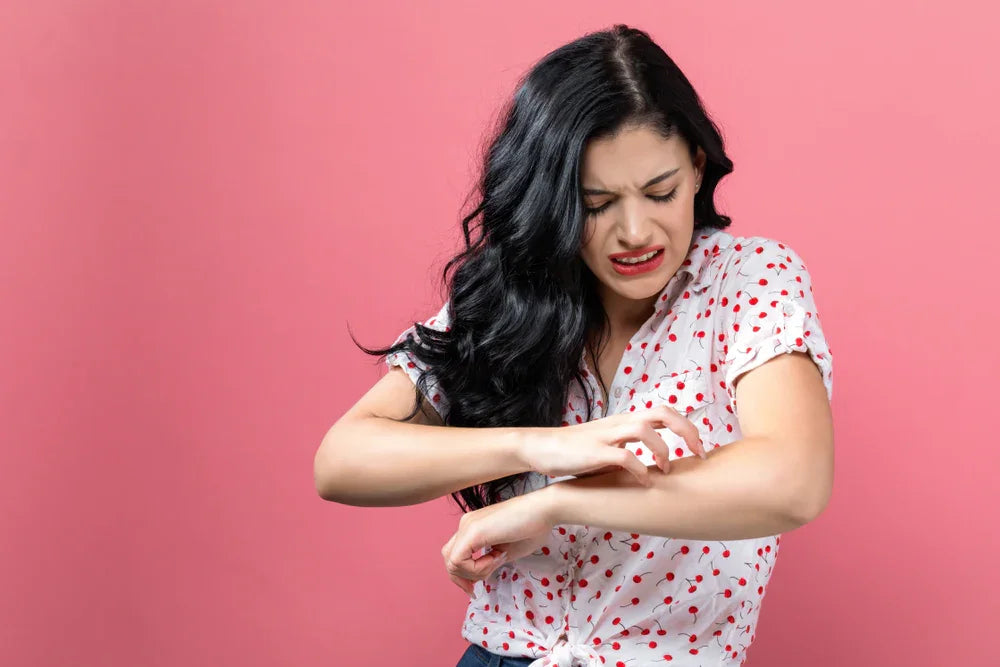 Woman with itchy skin scratching arm, eczema or allergy symptoms, on pink background