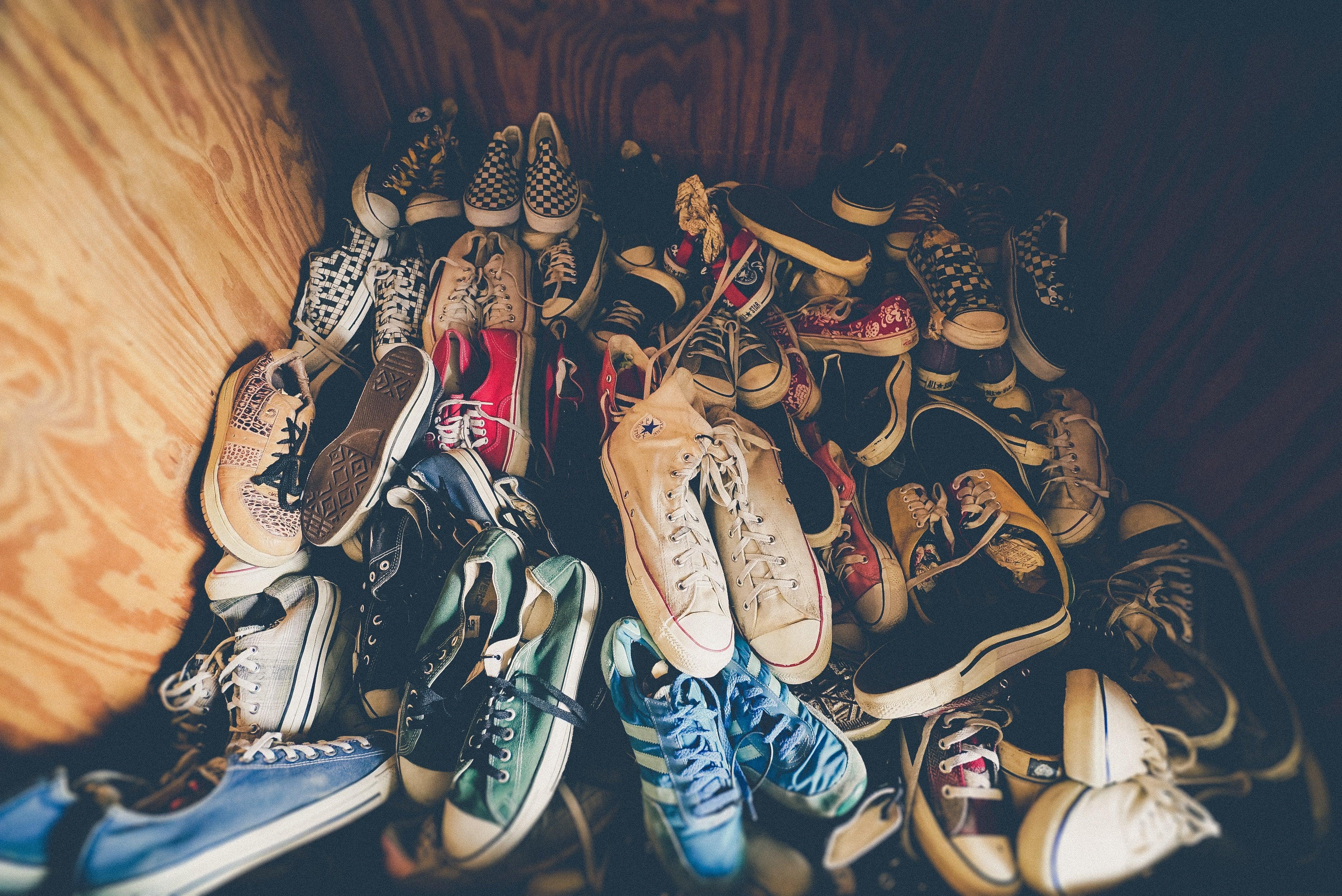 Assorted canvas sneakers in a pile against wooden background, casual footwear collection