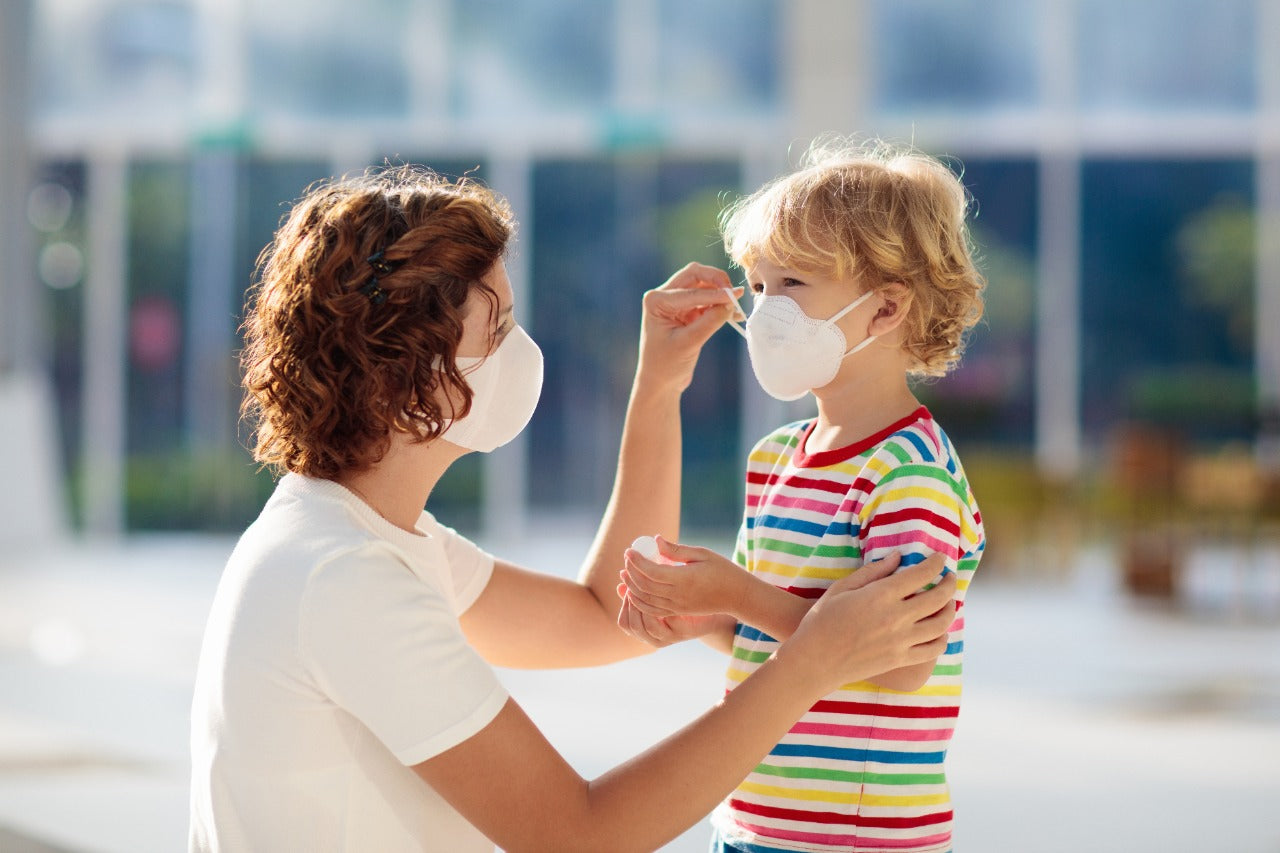 Mother and child wearing allergy-free cotton face masks indoors, child in striped shirt