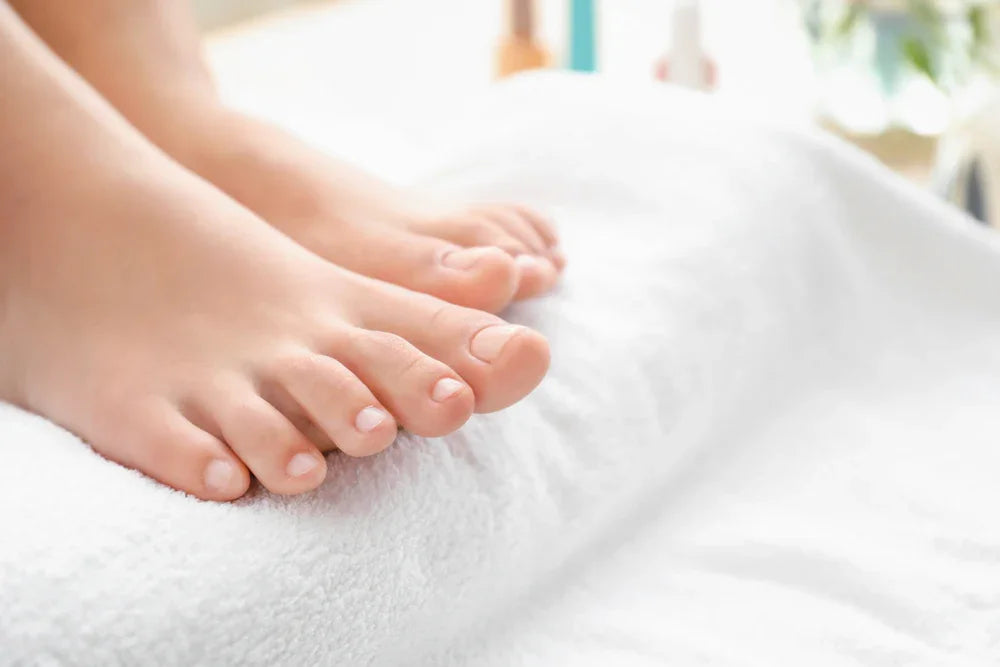 Bare feet resting on a soft white organic cotton towel, gentle care for sensitive skin