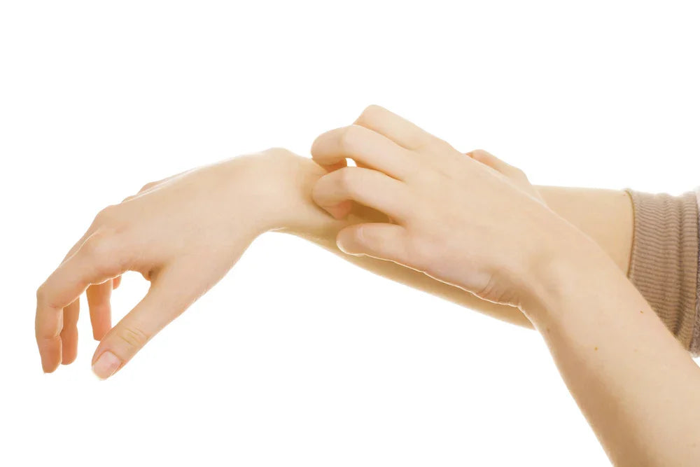 Person scratching wrist, showing skin irritation possibly from clothing allergy