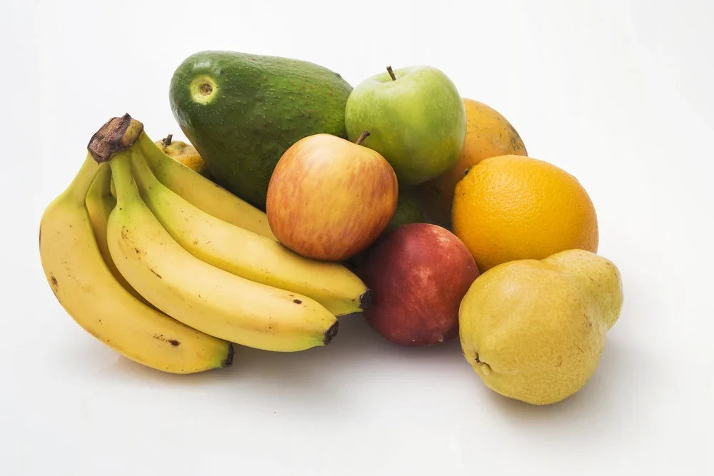 Assorted fresh fruits including bananas, apple, orange, pear, and avocado on white background