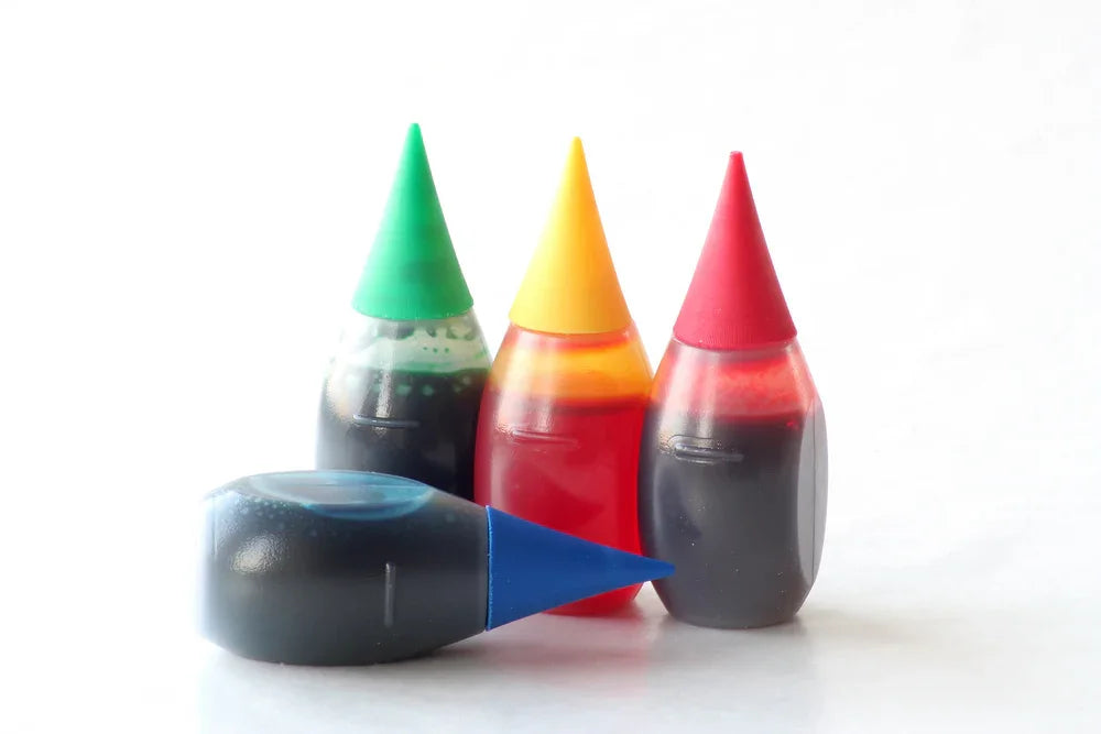 Colorful food dye bottles on white background, often used for hypoallergenic clothing dyes