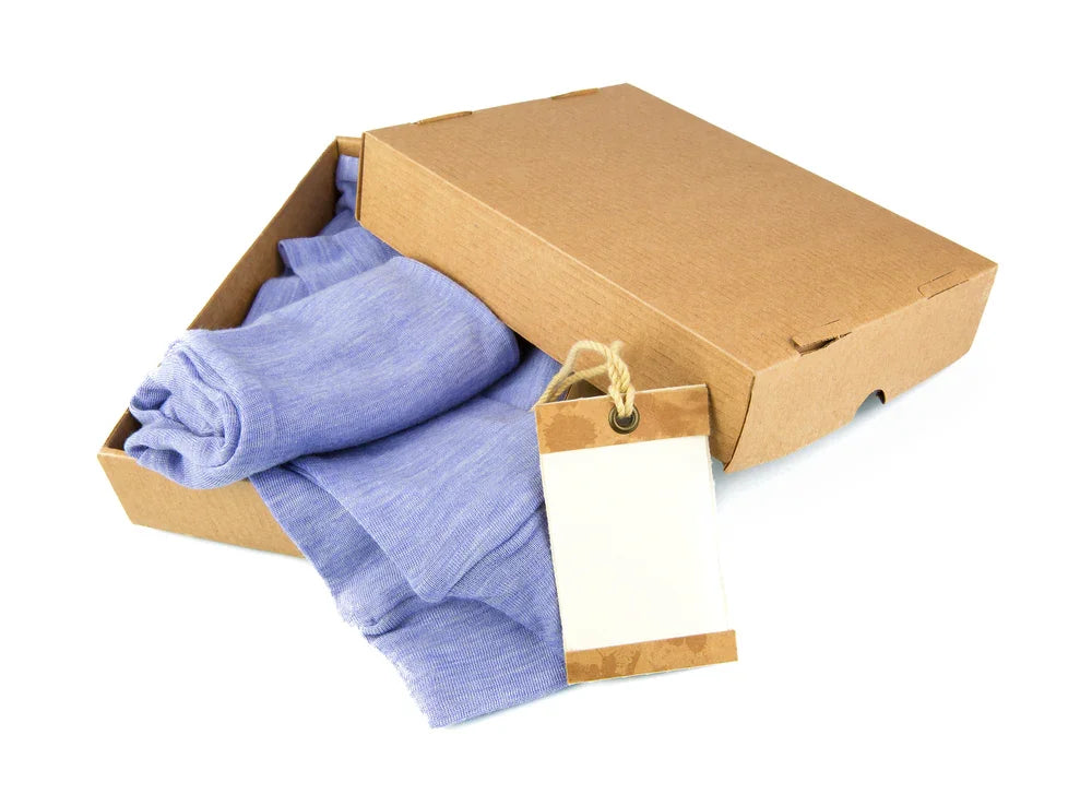 Blue hypoallergenic clothing folded in a brown box with blank tag, Cottonique allergy-free apparel