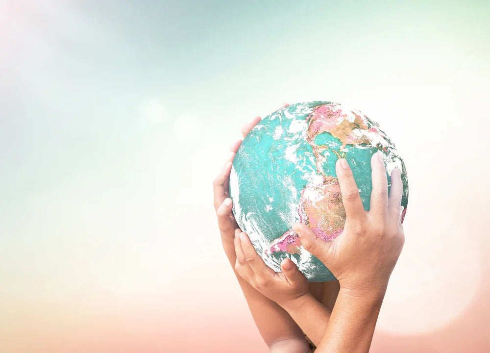 Multiple hands gently holding a globe, symbolizing sustainability and eco-friendly values.