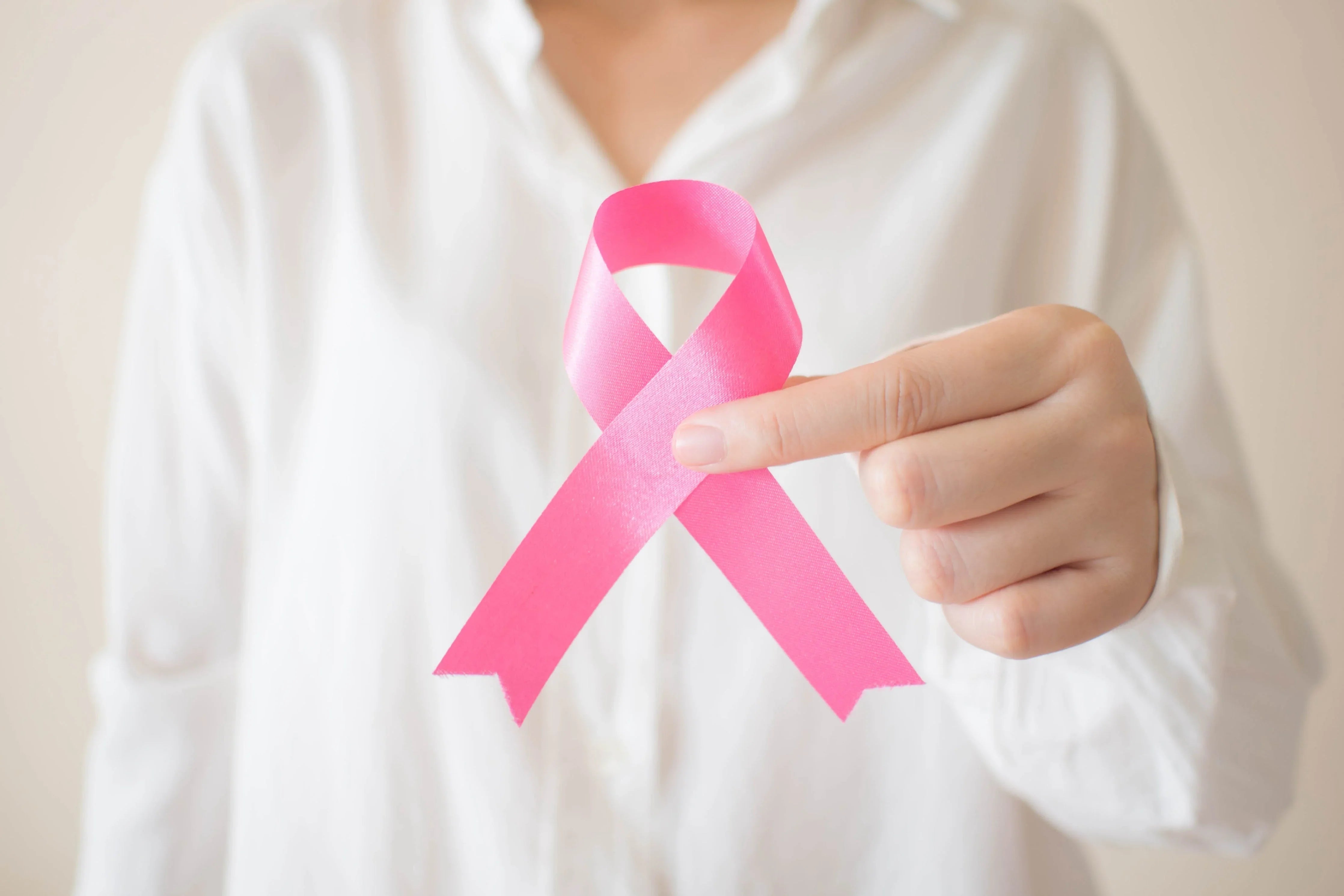 Person in white shirt holding pink ribbon symbol, allergy-free apparel support awareness