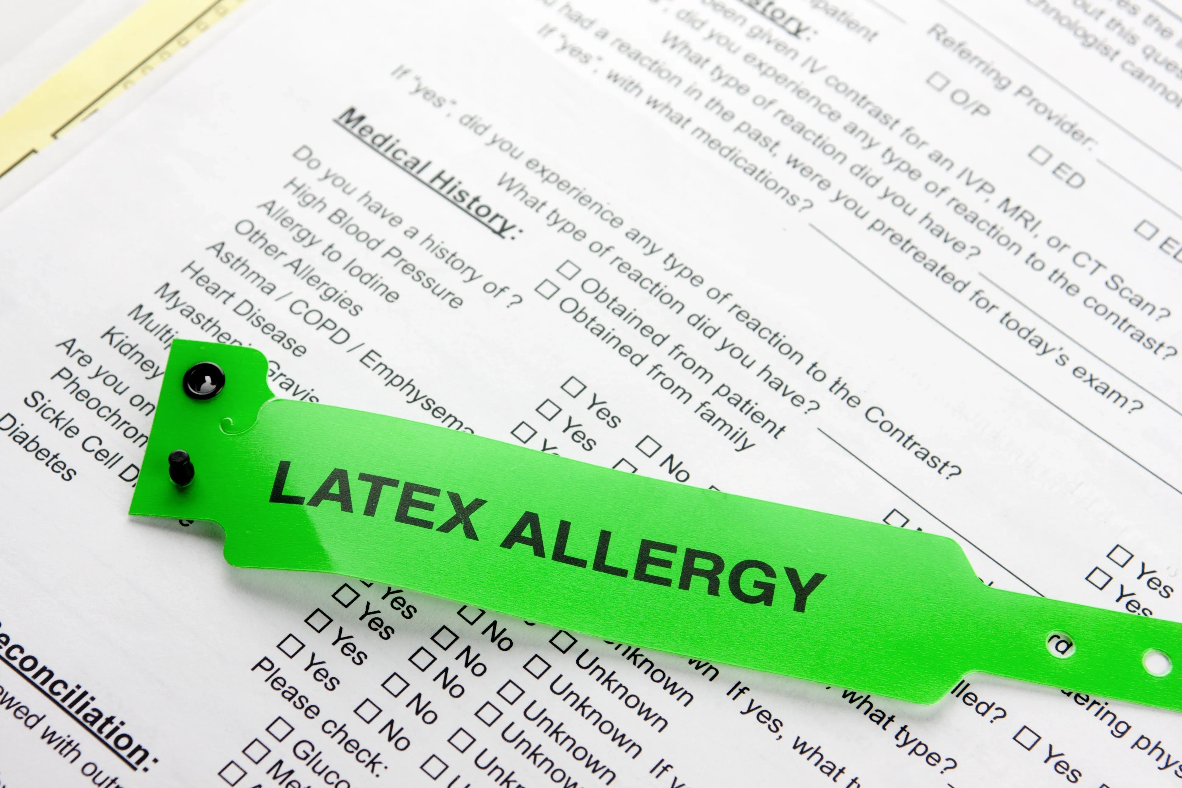 Green latex allergy wristband on medical history form, highlighting allergy awareness
