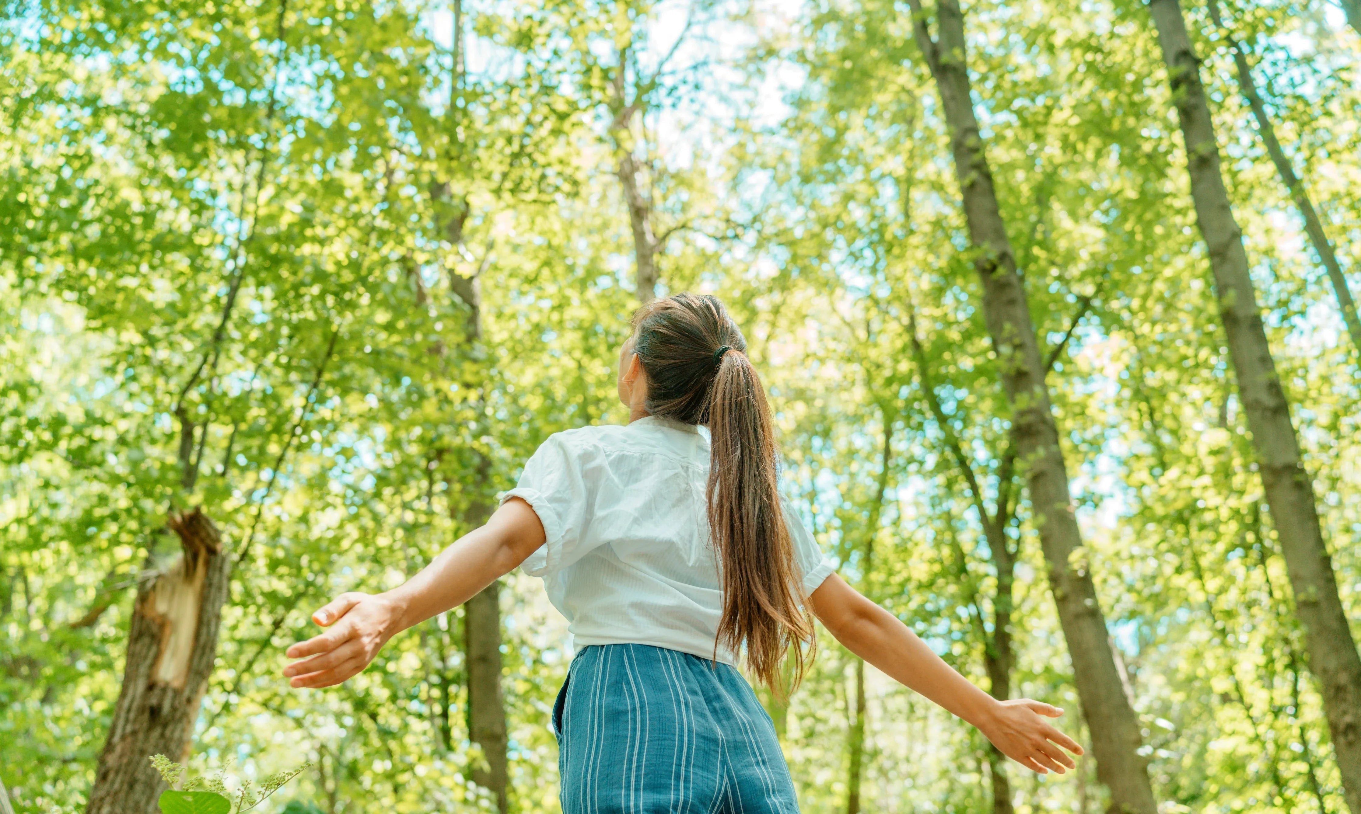 Woman in allergy-free cotton apparel enjoying nature in a sunlit forest