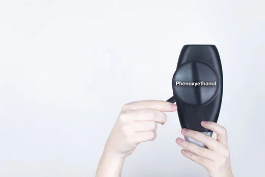 Hands holding a black cosmetic bottle labeled phenoxyethanol, related to hypoallergenic apparel