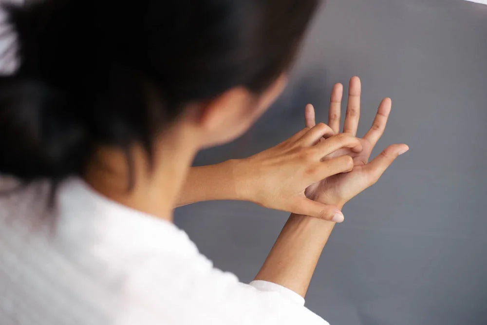 Woman scratching hand, possible skin allergy, hypoallergenic clothing context