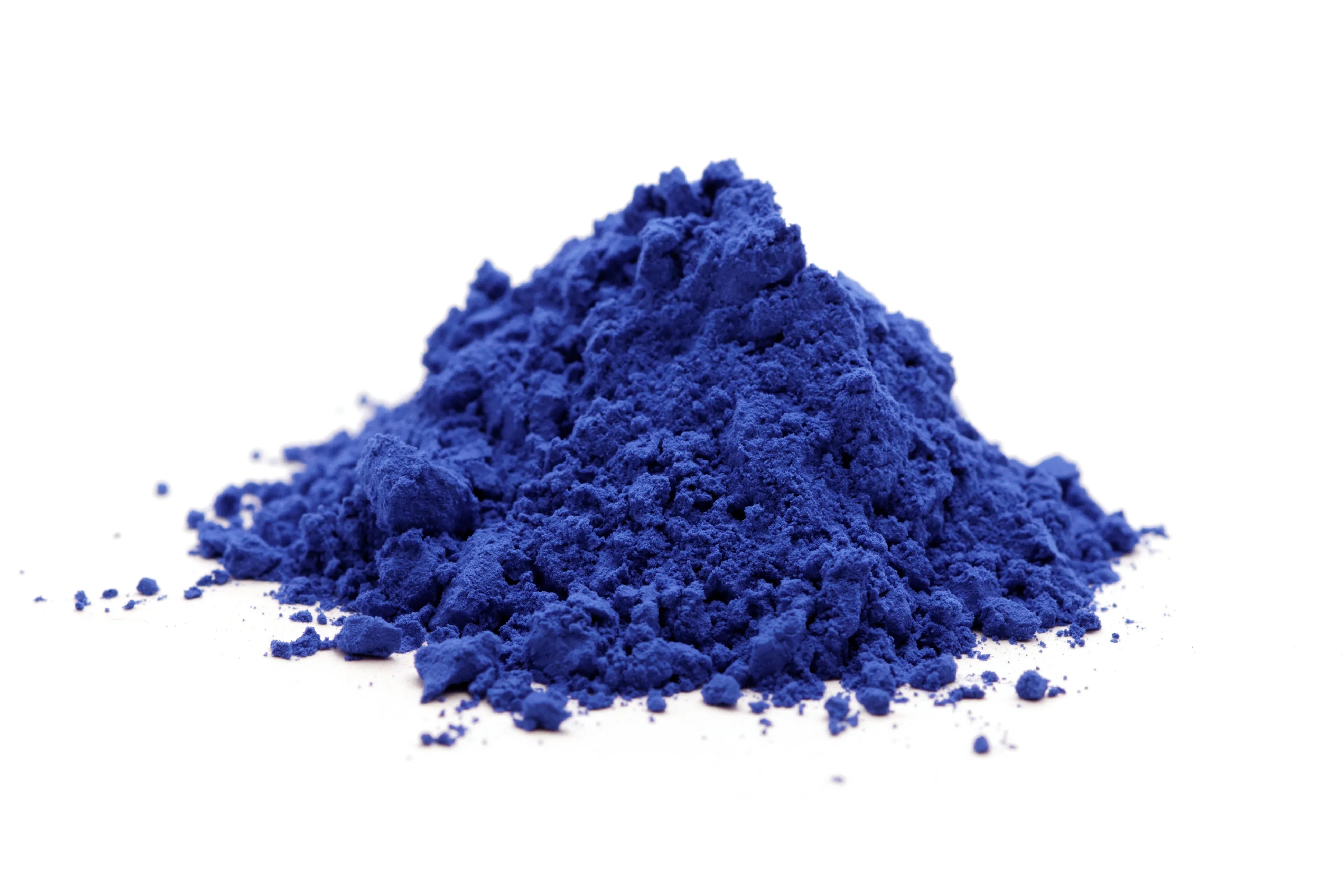 Pile of vibrant blue fabric dye powder on a white surface for hypoallergenic apparel