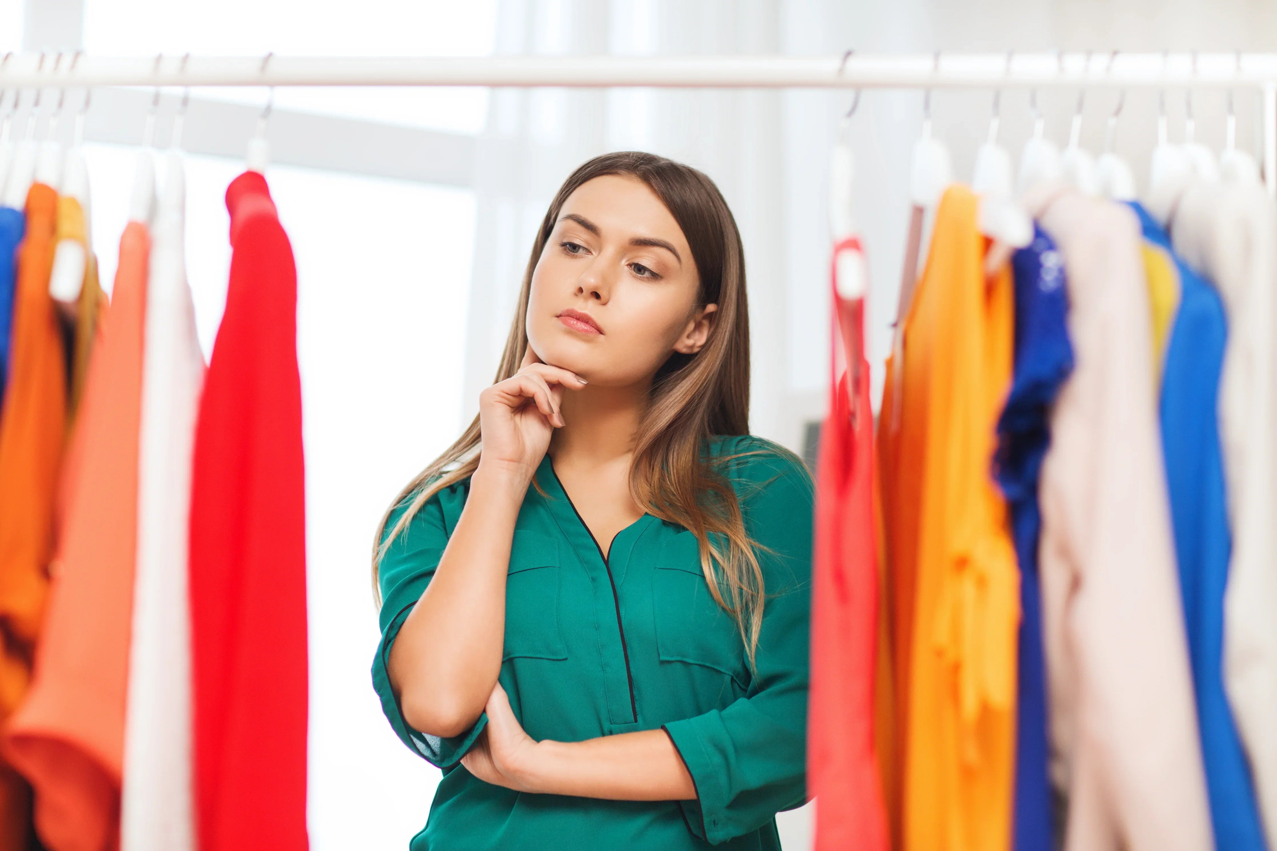 Woman choosing colorful clothes on rack, shopping for allergy-friendly organic cotton apparel