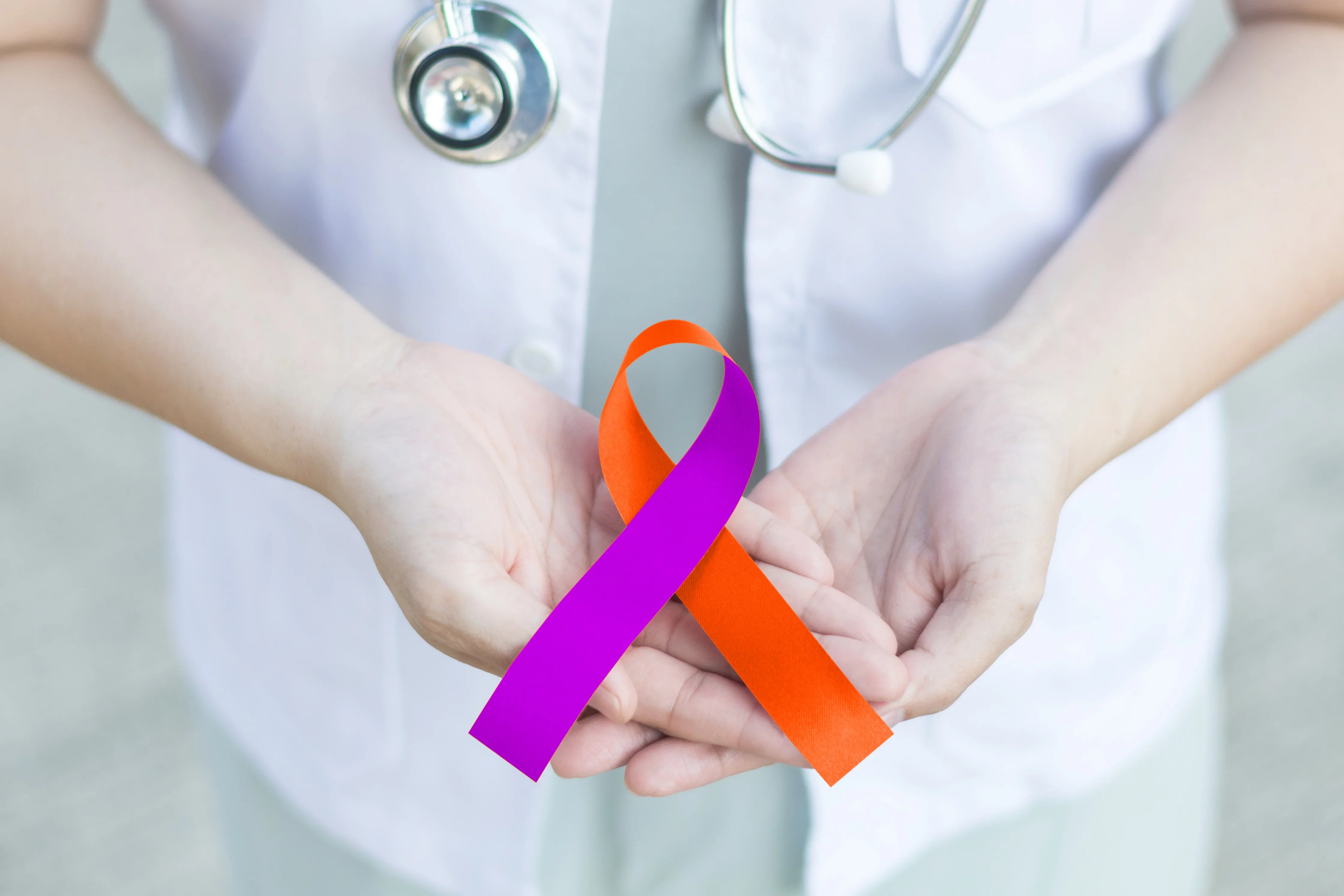 Doctor holding orange and purple awareness ribbon for healthcare and allergy support