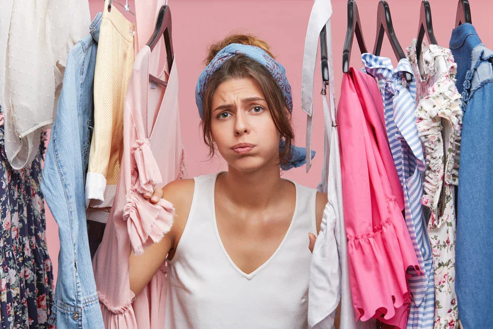 Woman looking frustrated in closet surrounded by colorful clothing, highlighting apparel allergy concerns