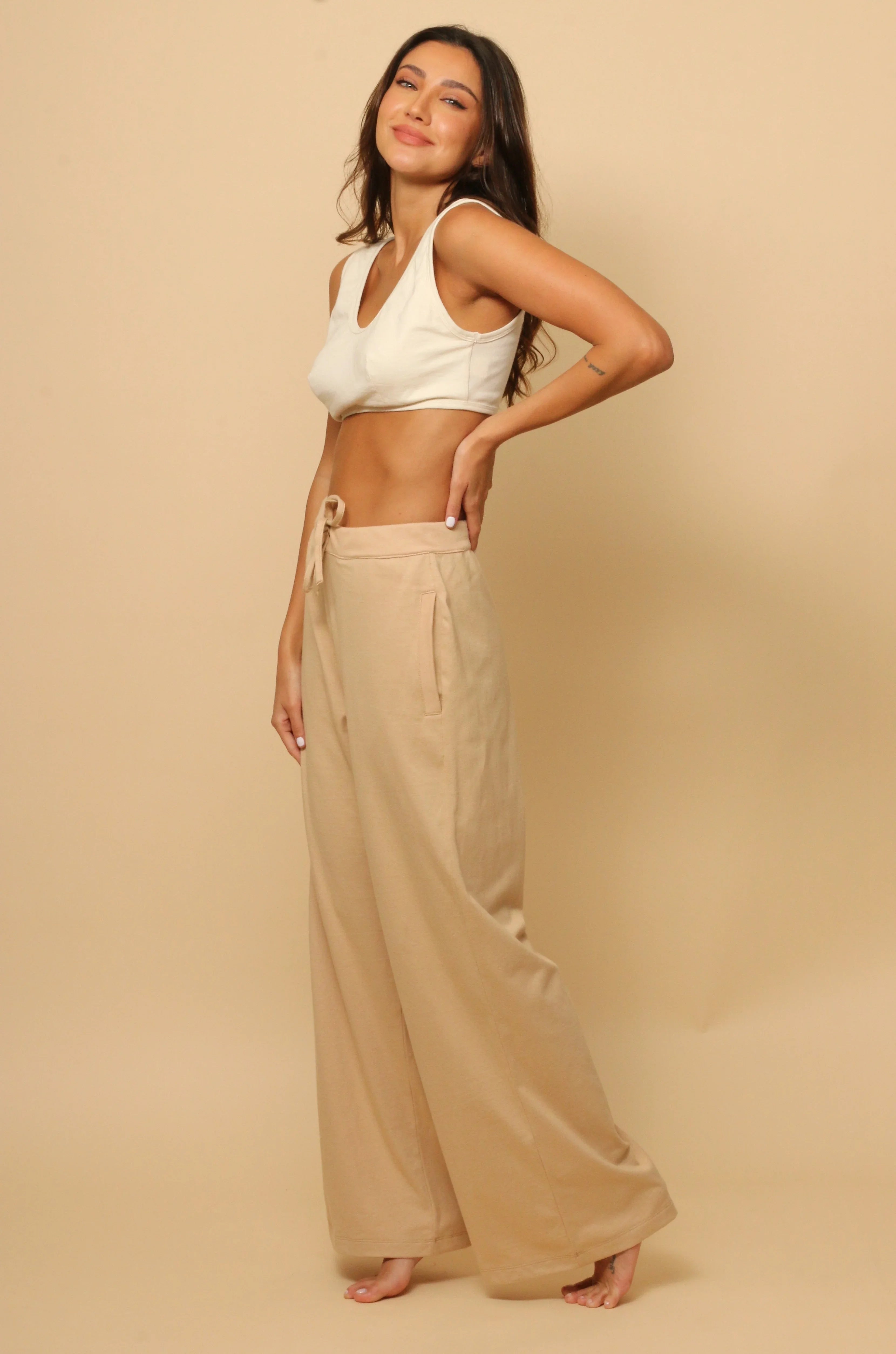 Woman wearing allergy-free Cottonique beige lounge pants and cream crop top