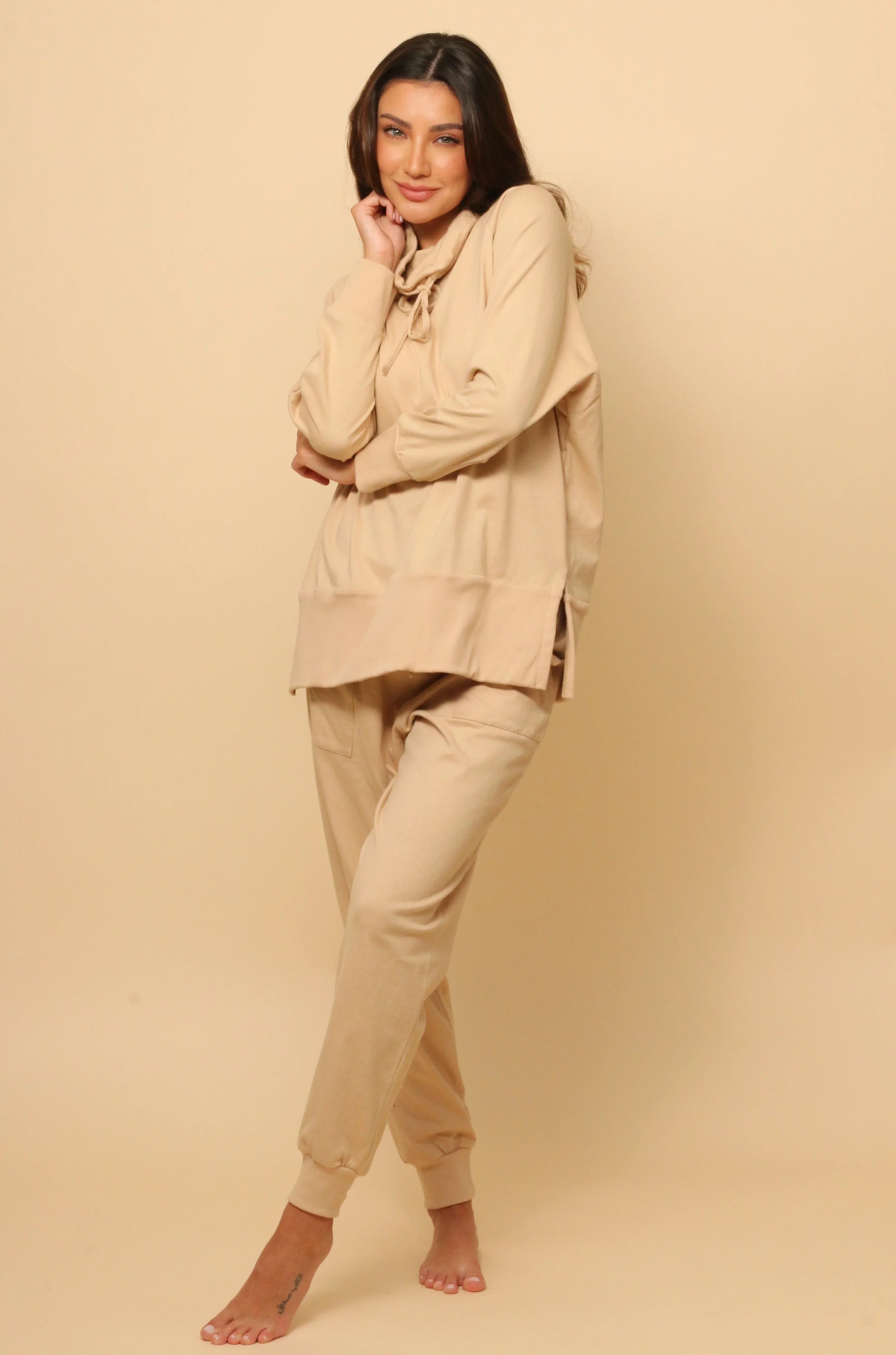 Woman wearing beige hypoallergenic cotton loungewear from Cottonique against a neutral background
