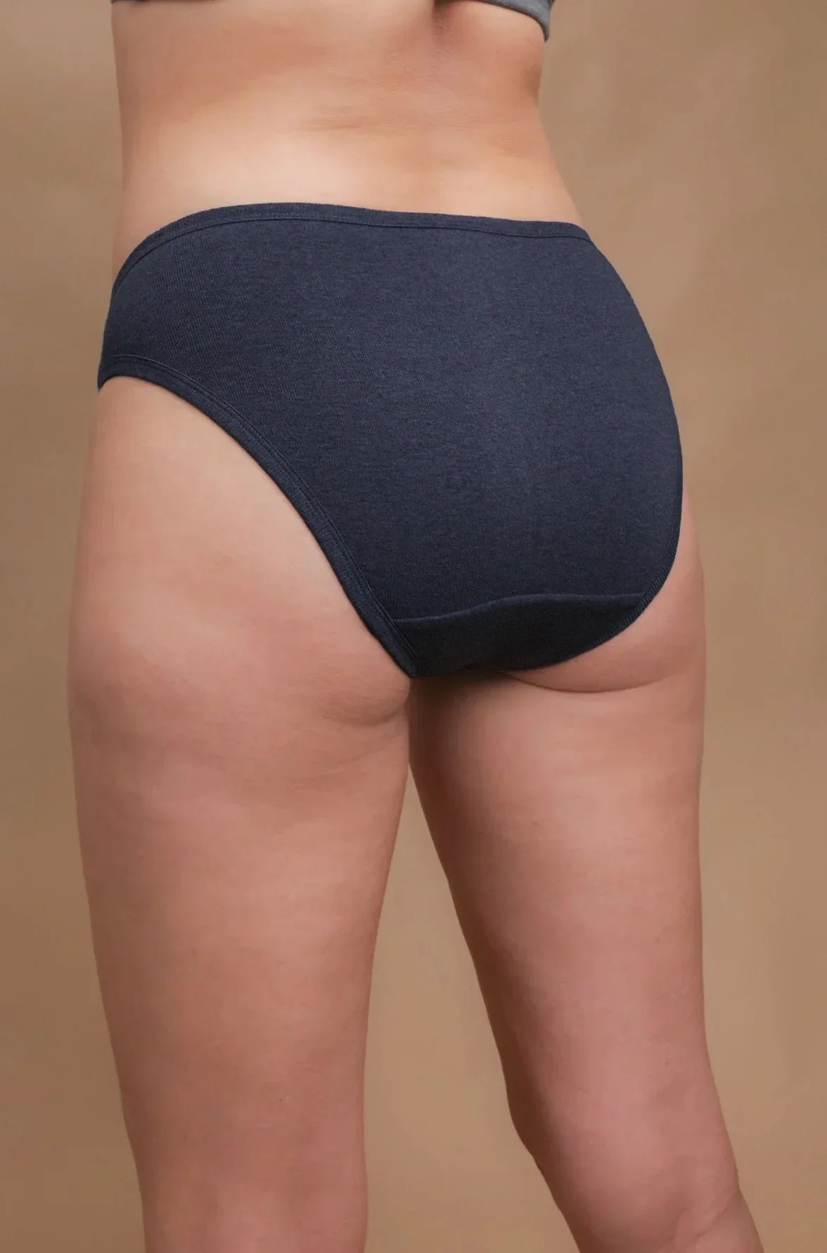 Back view of a woman wearing dark blue hypoallergenic cotton briefs by Cottonique