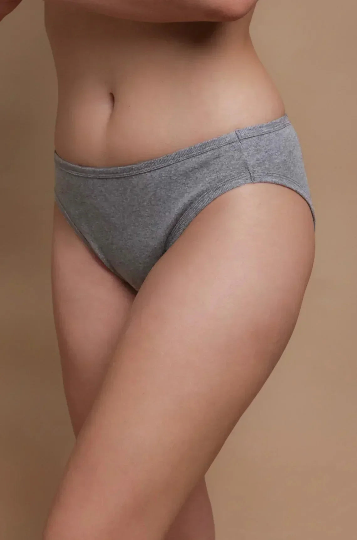 Woman wearing gray hypoallergenic cotton underwear by Cottonique against neutral background