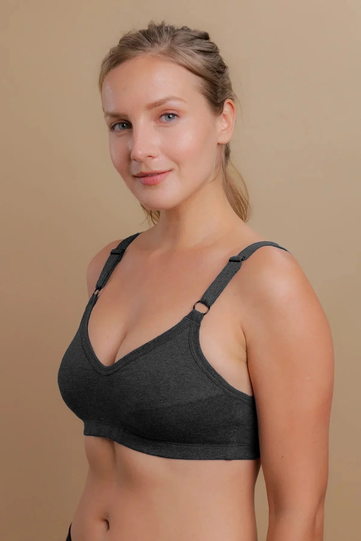 Woman wearing a dark gray hypoallergenic cotton bra by Cottonique against tan background