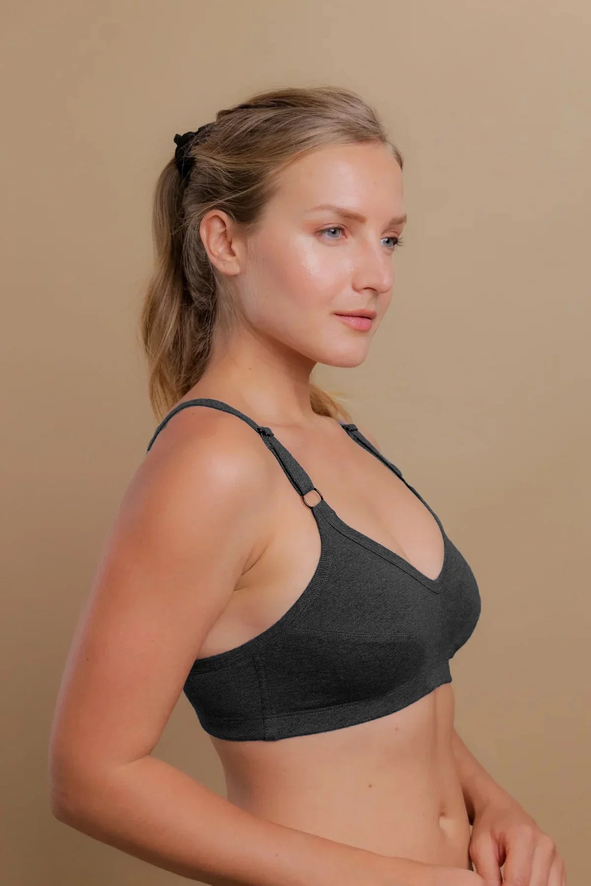 Woman wearing a dark gray hypoallergenic cotton bra by Cottonique against a beige background
