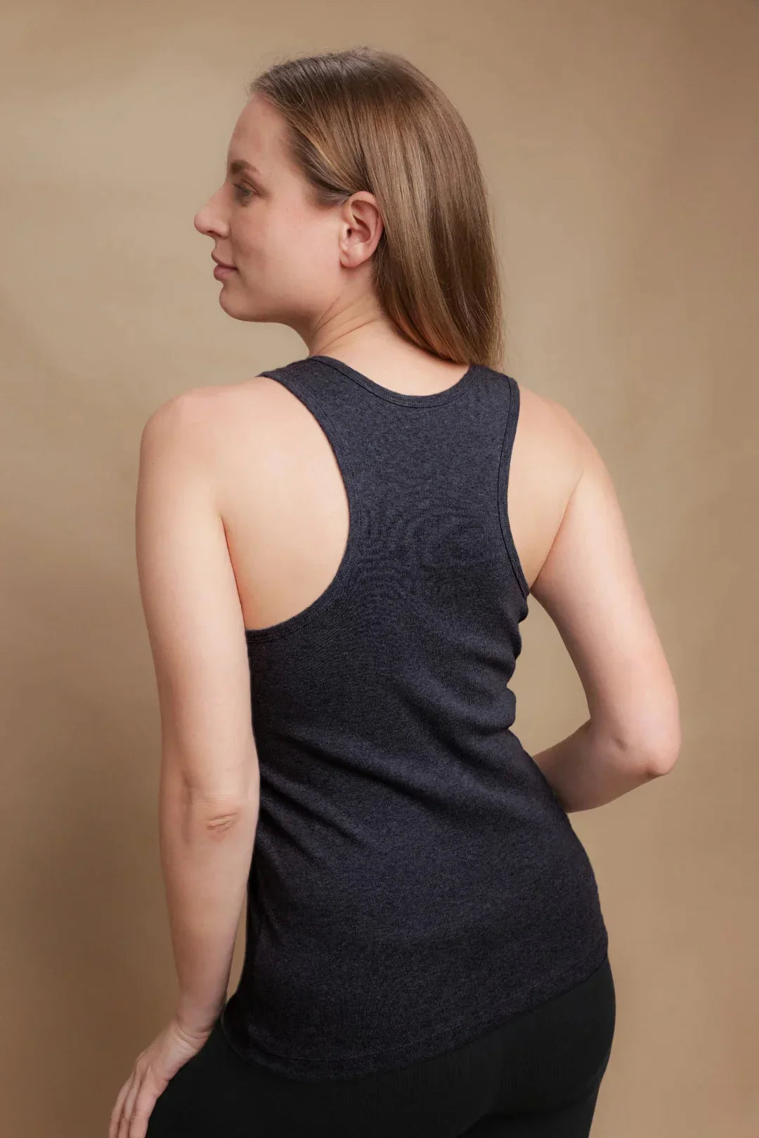 Woman wearing a dark hypoallergenic cotton racerback tank top by Cottonique, back view.