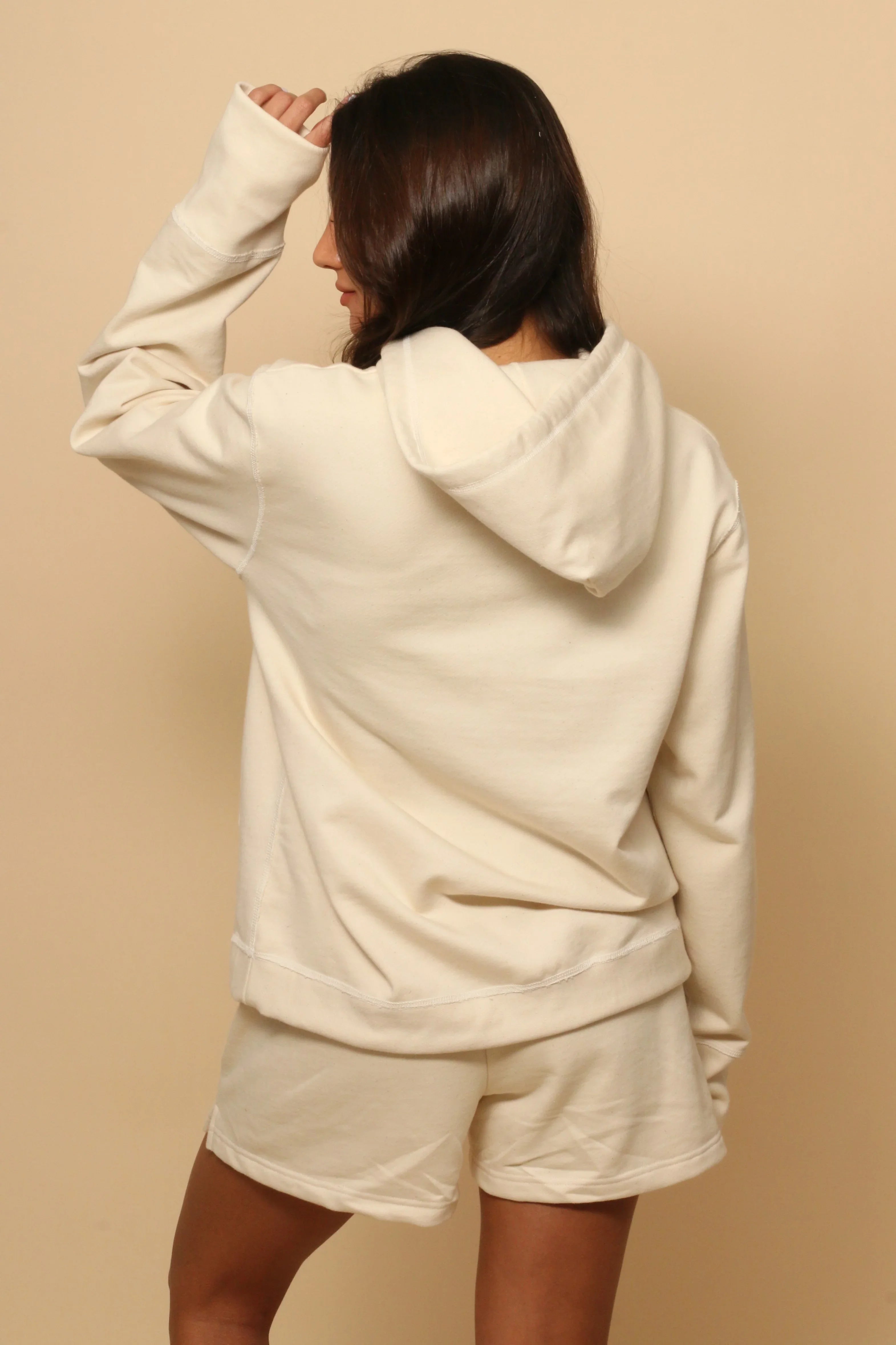 Woman wearing cream organic cotton hoodie and shorts, allergy-friendly clothing