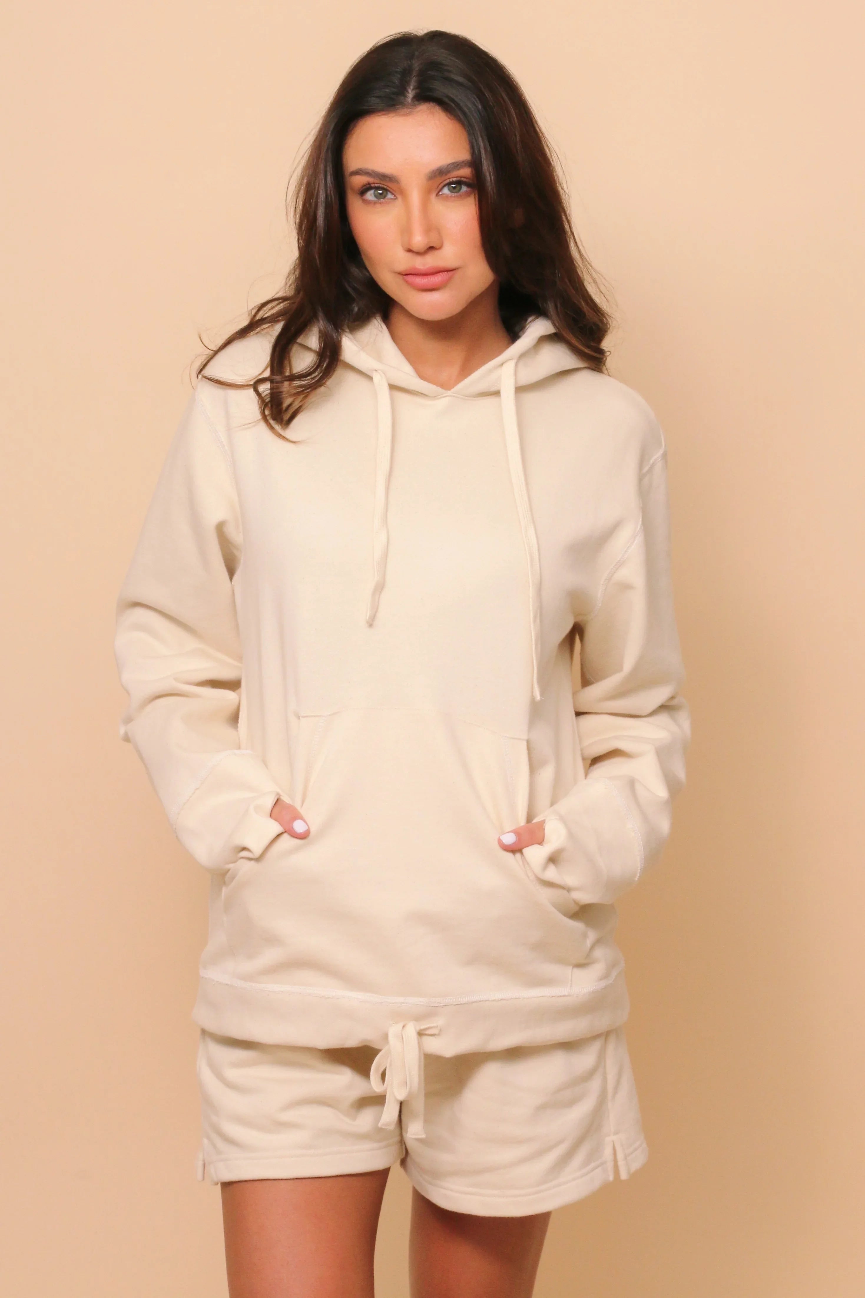 Woman wearing an off-white organic cotton hoodie and shorts, suitable for sensitive skin