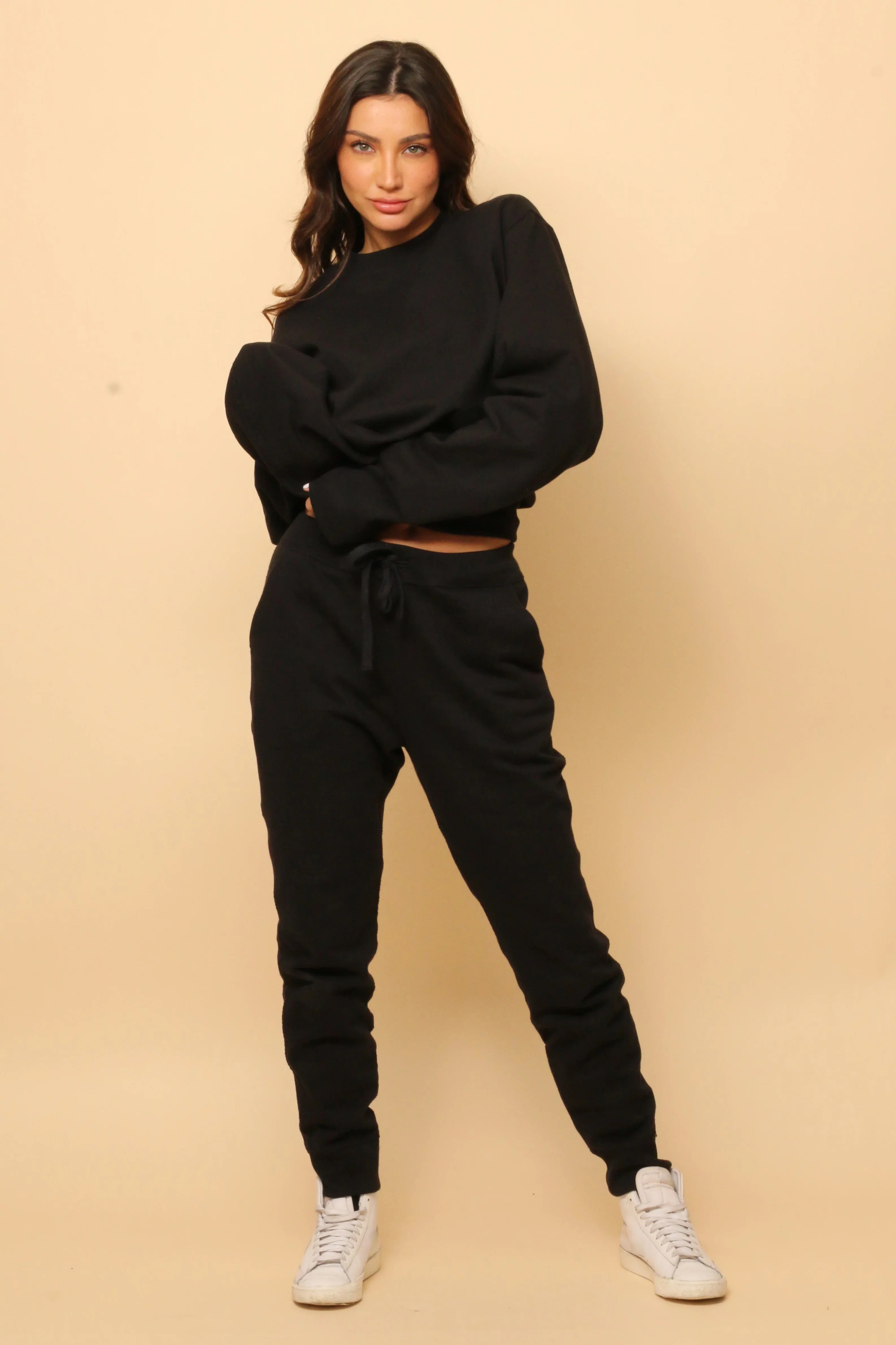 Woman modeling black hypoallergenic cotton sweatsuit from Cottonique against beige background