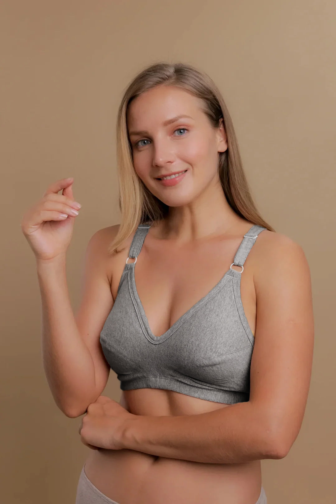 Woman wearing a gray organic cotton wireless bra for sensitive skin on beige background