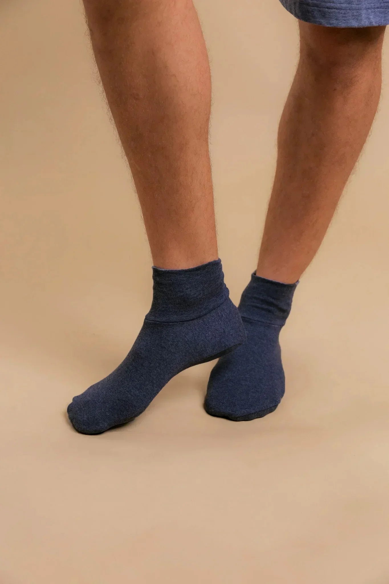 Man wearing blue hypoallergenic cotton ankle socks from Cottonique on beige background