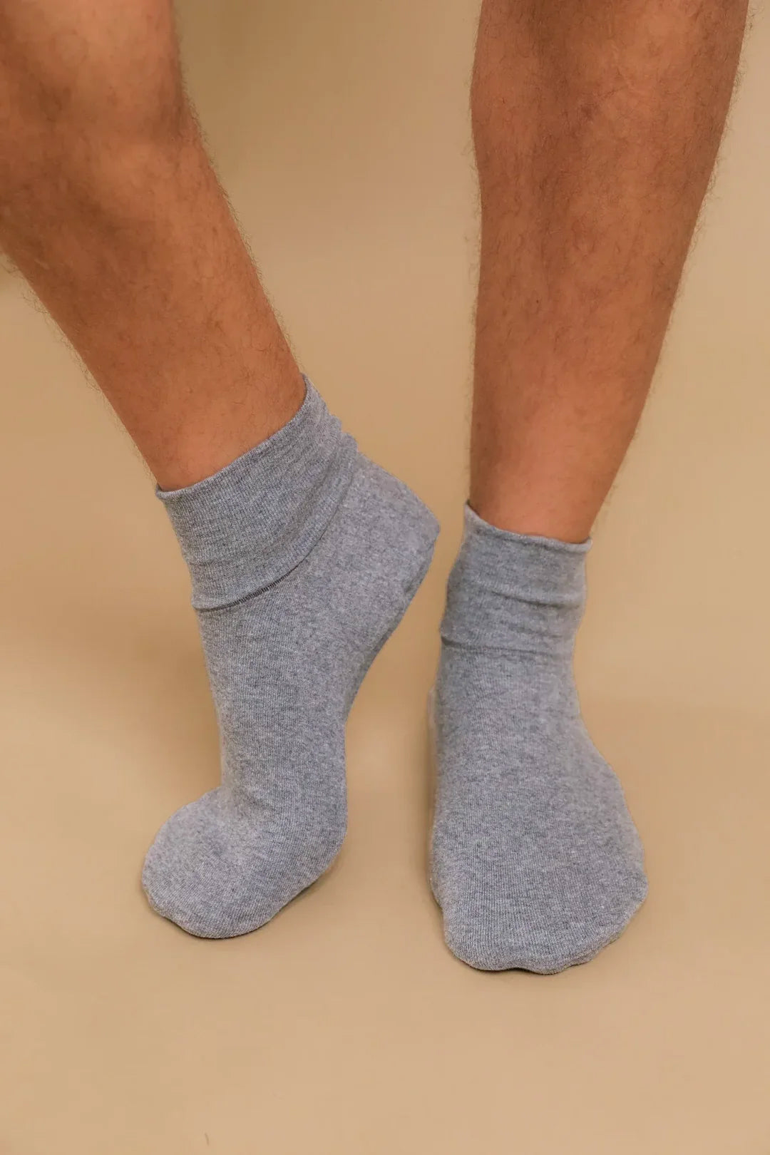 Gray organic cotton crew socks for sensitive skin on model feet against beige background