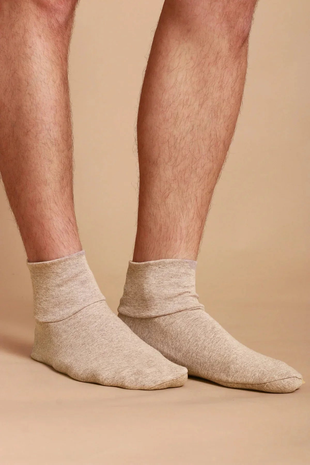 Person wearing beige hypoallergenic cotton socks from Cottonique on neutral background