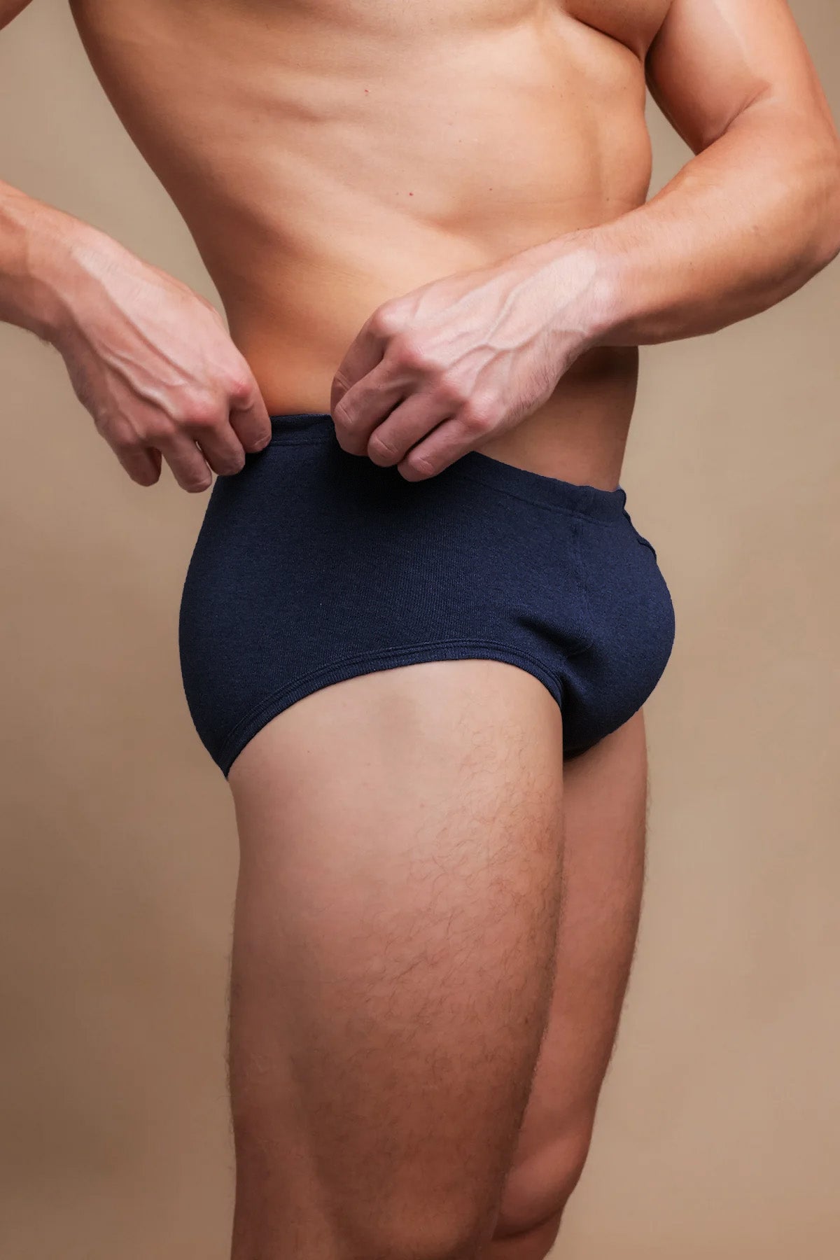 Man wearing navy hypoallergenic cotton briefs from Cottonique, side view.