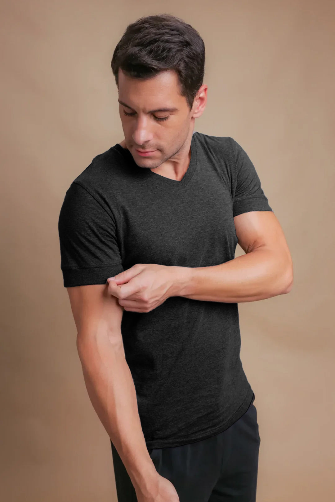 Man wearing black hypoallergenic cotton V-neck T-shirt from Cottonique against beige background