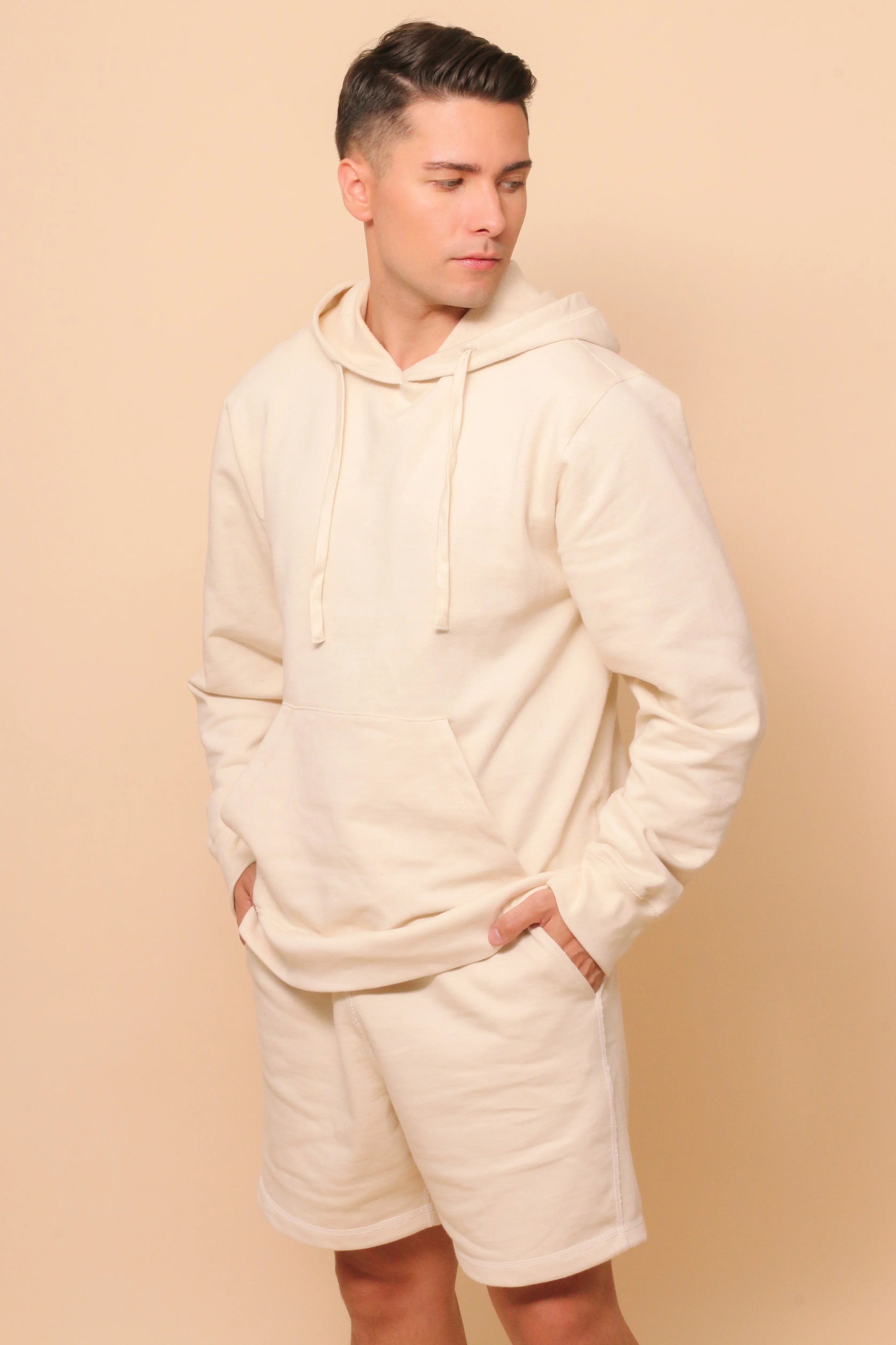 Man wearing allergy-free cotton hoodie and shorts from Cottonique, neutral background
