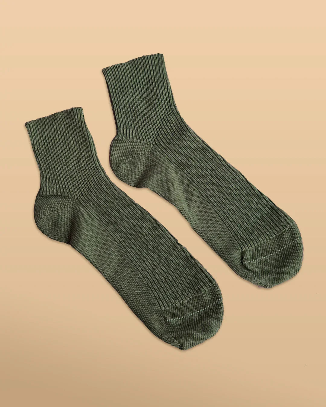 Green hypoallergenic cotton socks from Cottonique on a beige background