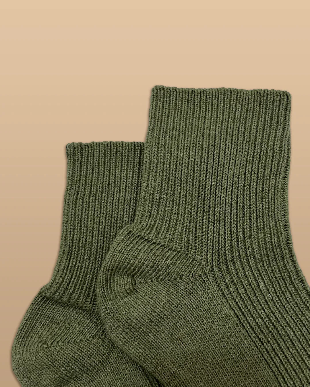 Olive green hypoallergenic cotton socks from Cottonique against a beige background