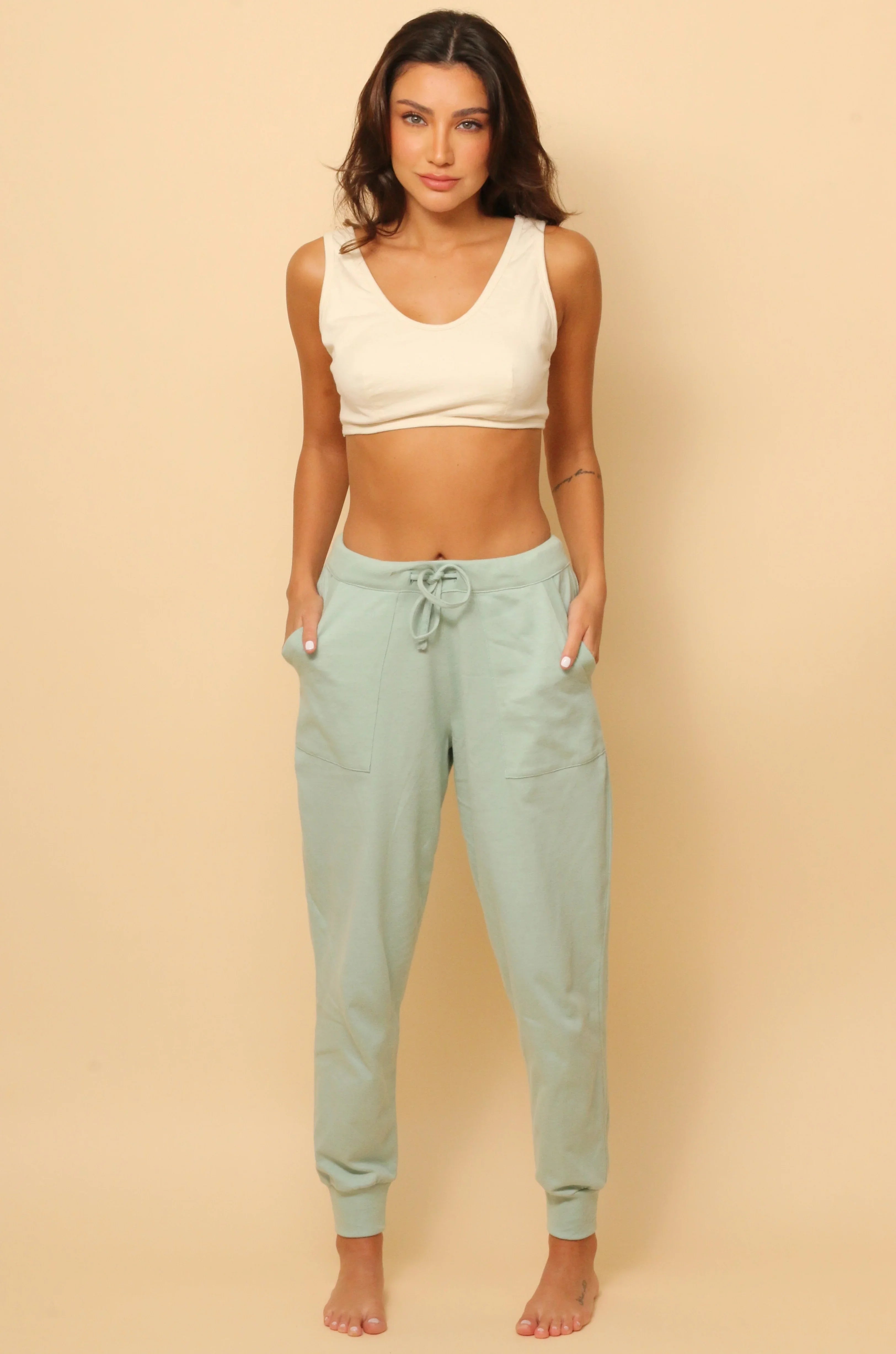 Woman wearing allergy-free Cottonique hypoallergenic mint green jogger pants and ivory crop top