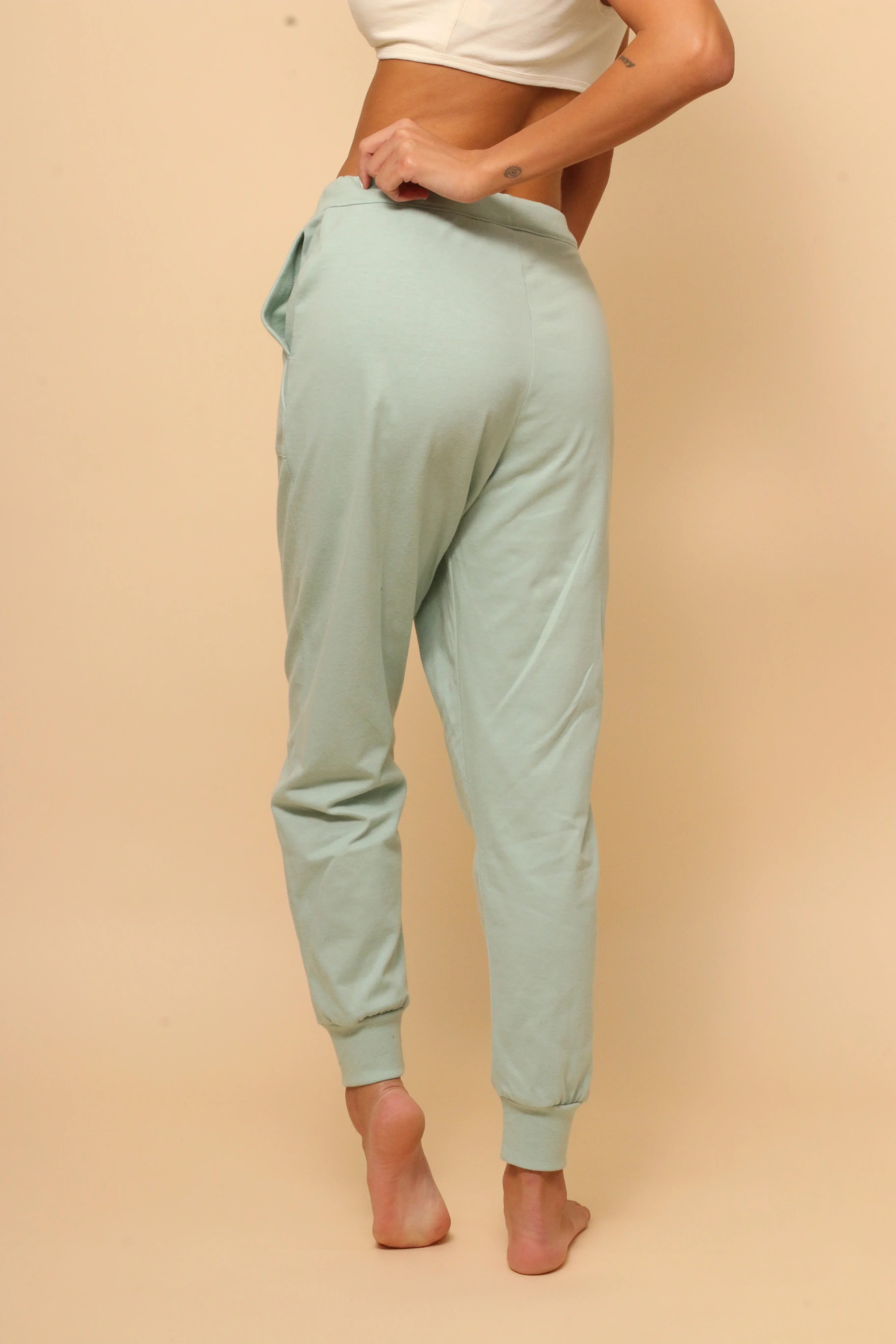 Woman wearing light green hypoallergenic cotton jogger pants by Cottonique, rear view