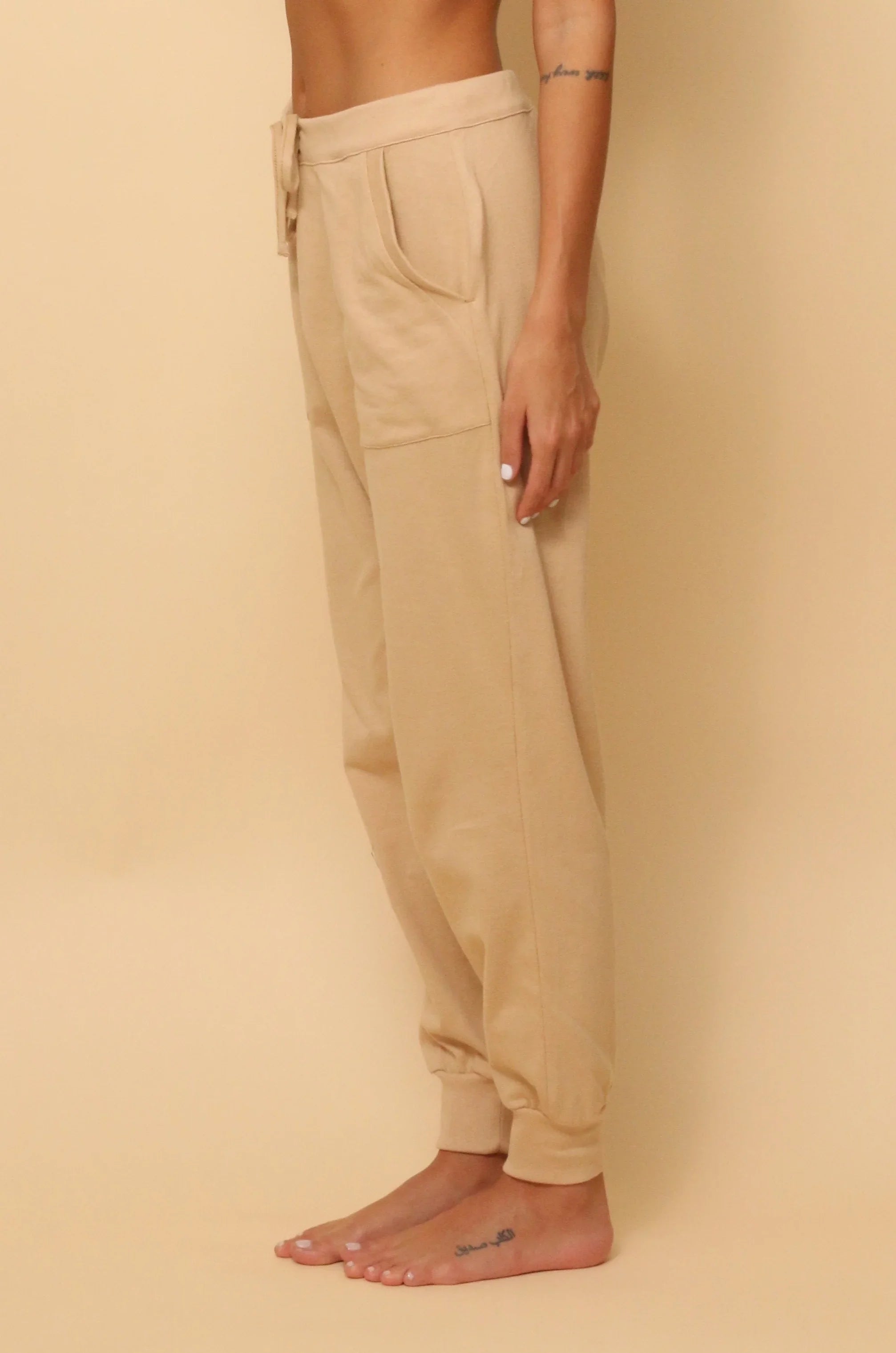Beige hypoallergenic cotton jogger pants for women, modeled barefoot, Cottonique apparel