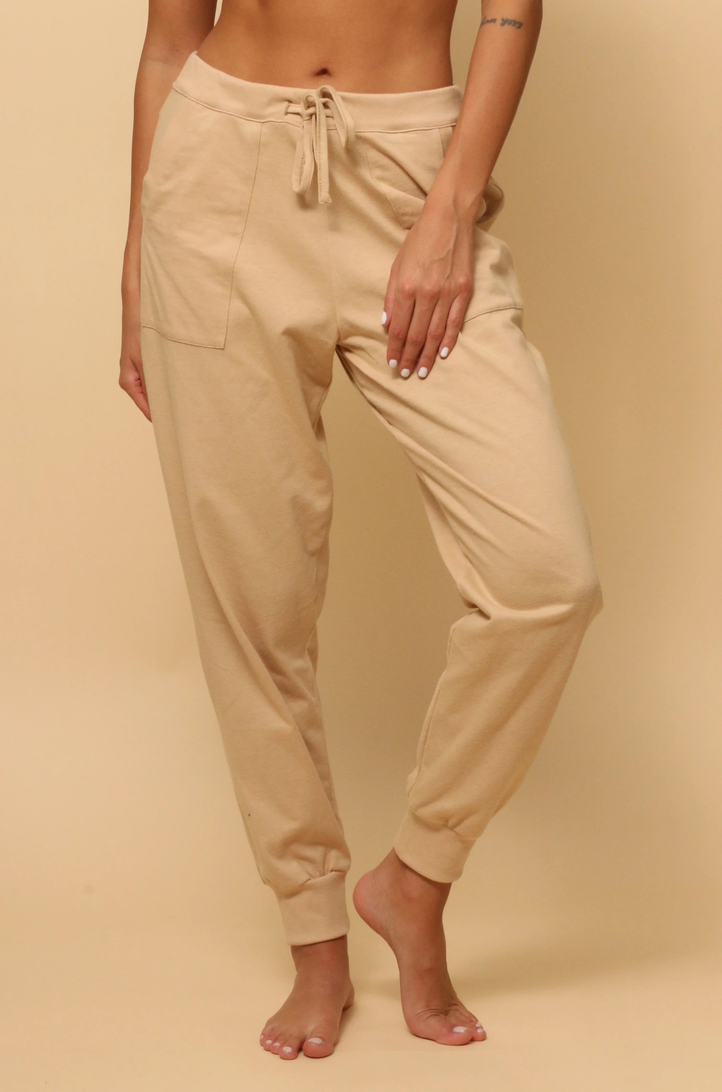 Woman wearing beige hypoallergenic cotton jogger pants from Cottonique on a neutral background