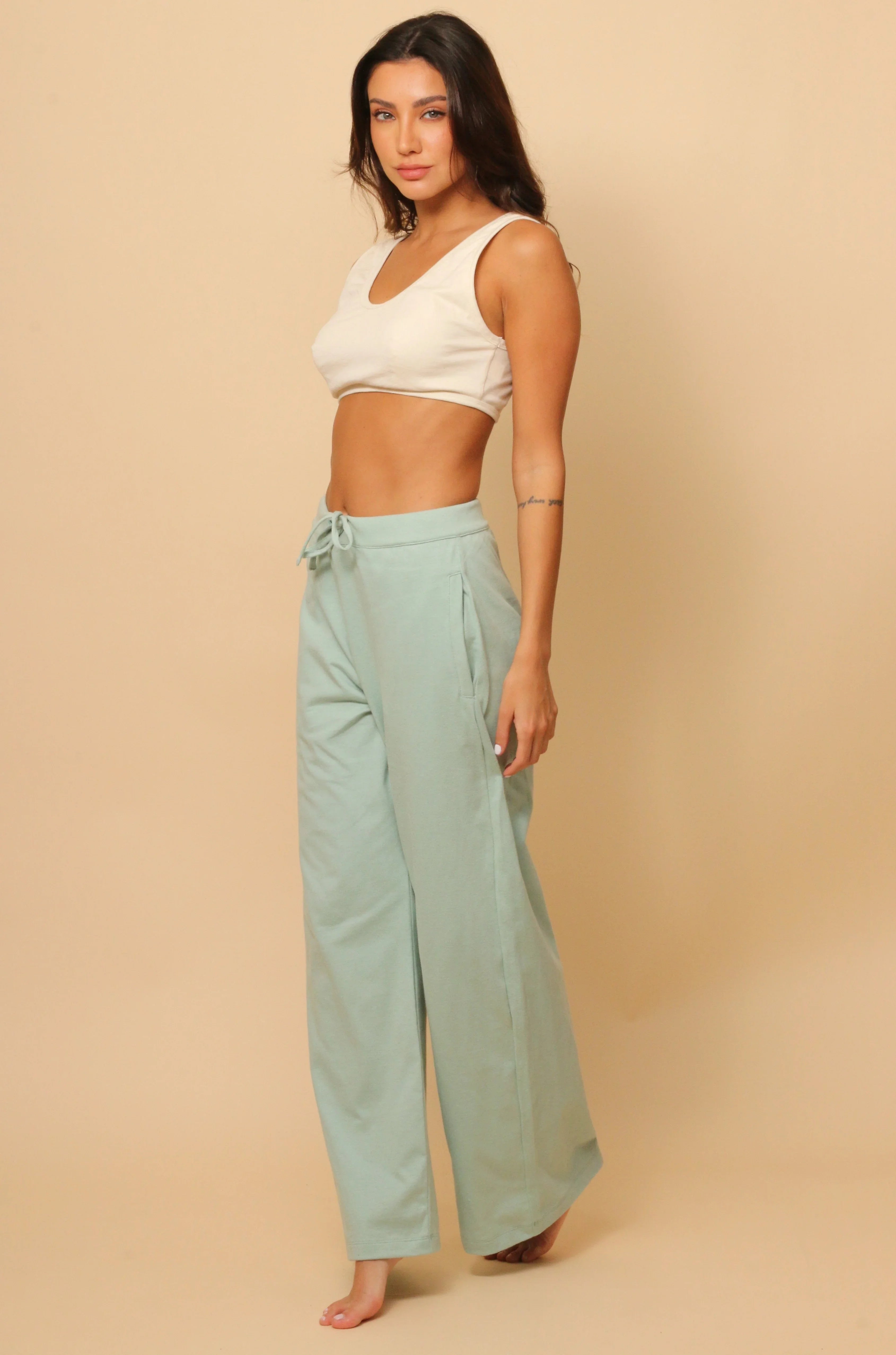 Woman wearing allergy-free Cottonique mint green lounge pants and cream crop top