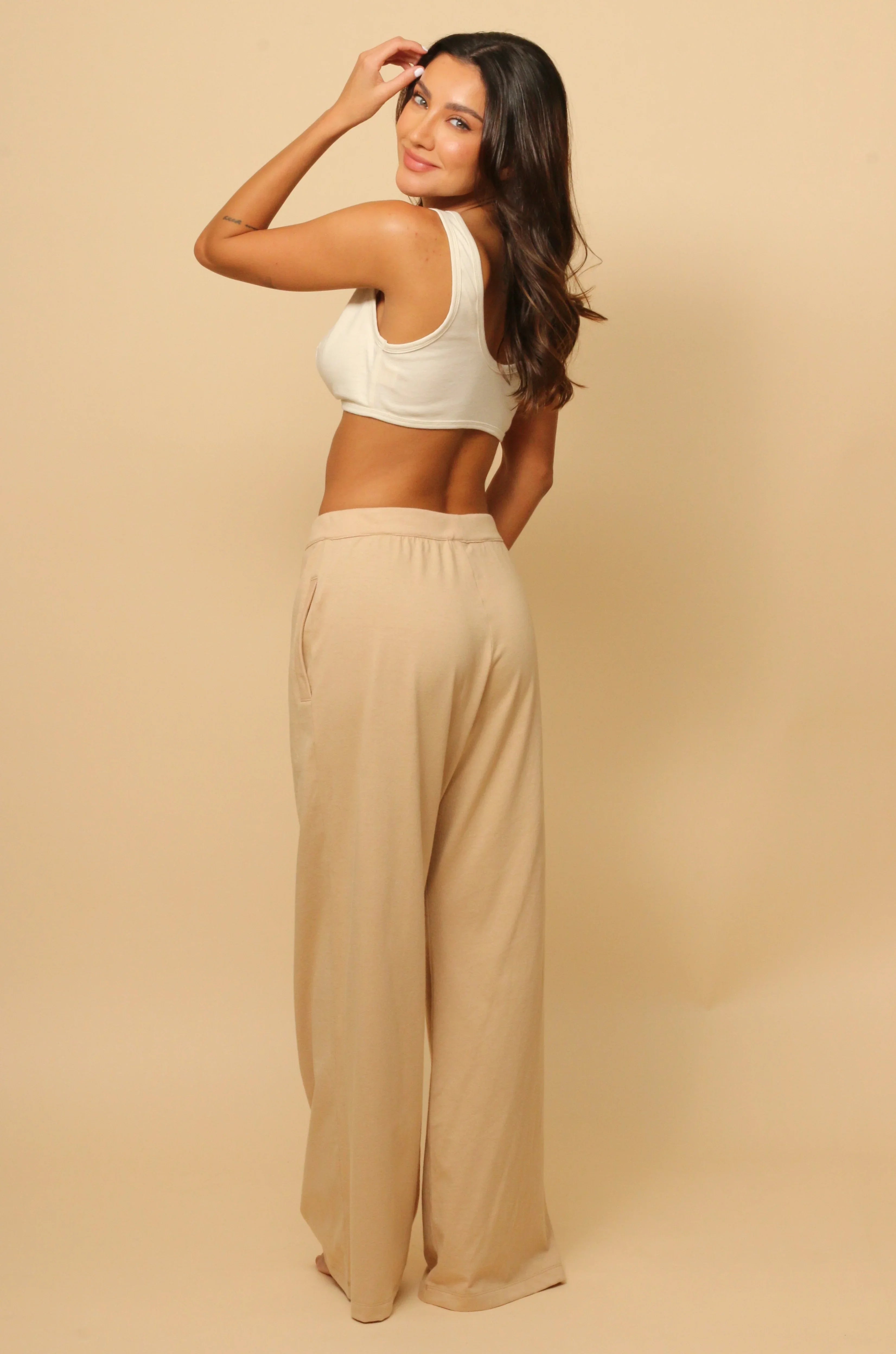 Woman modeling hypoallergenic beige lounge pants and white crop top from Cottonique