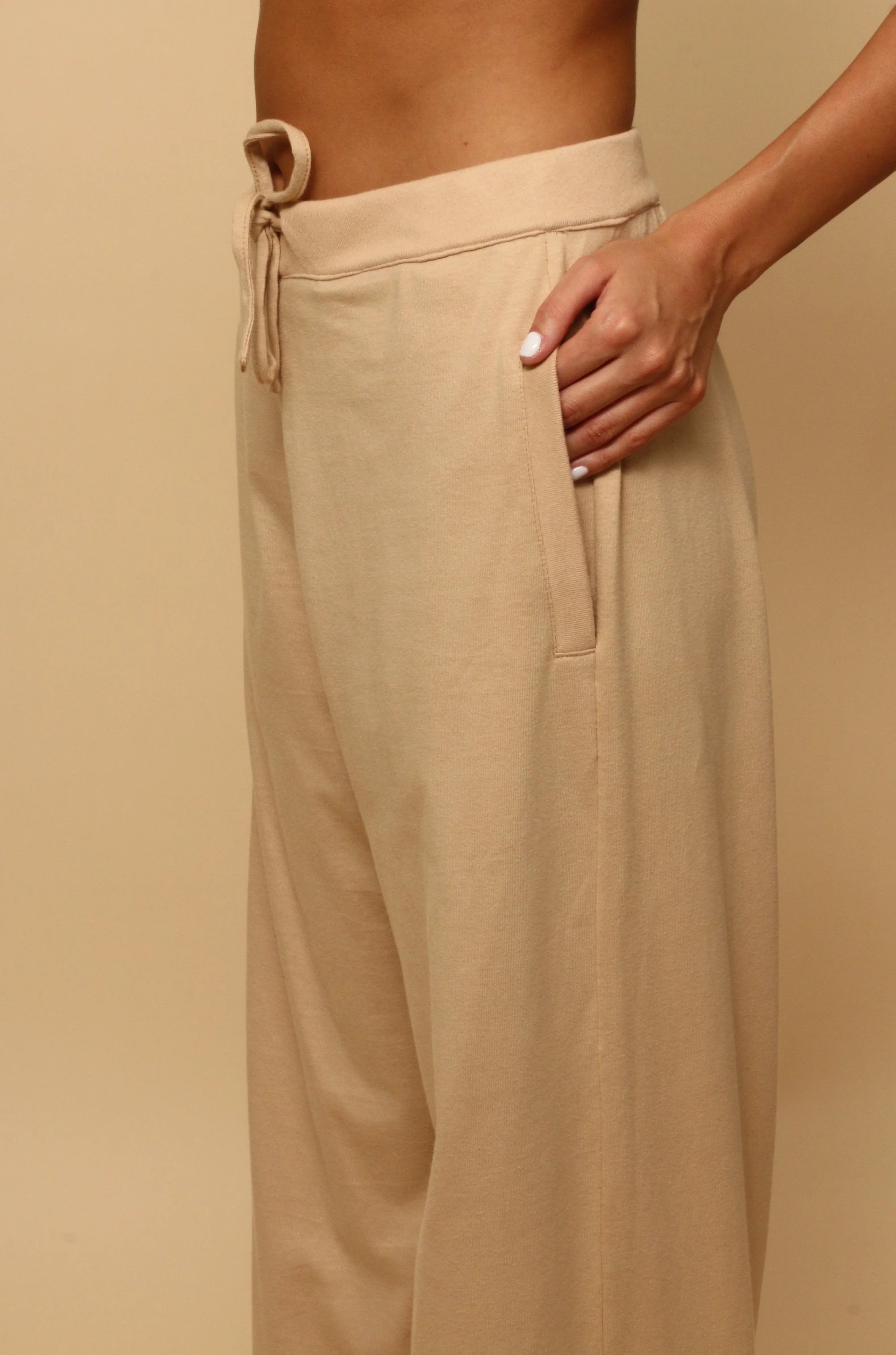 Woman wearing beige hypoallergenic drawstring cotton pants by Cottonique, hand in pocket