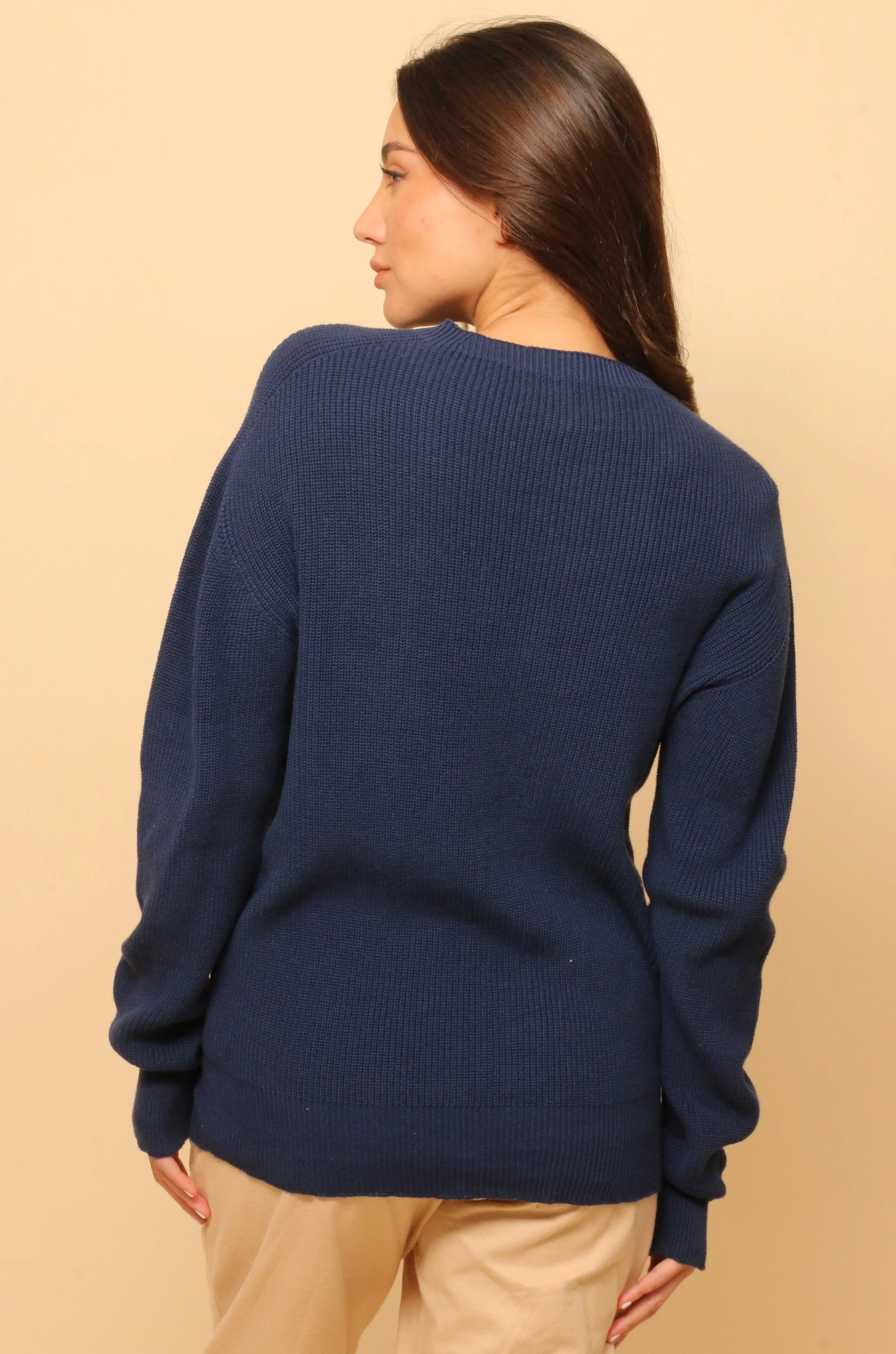 Woman wearing a navy blue organic cotton knit sweater, shown from the back.