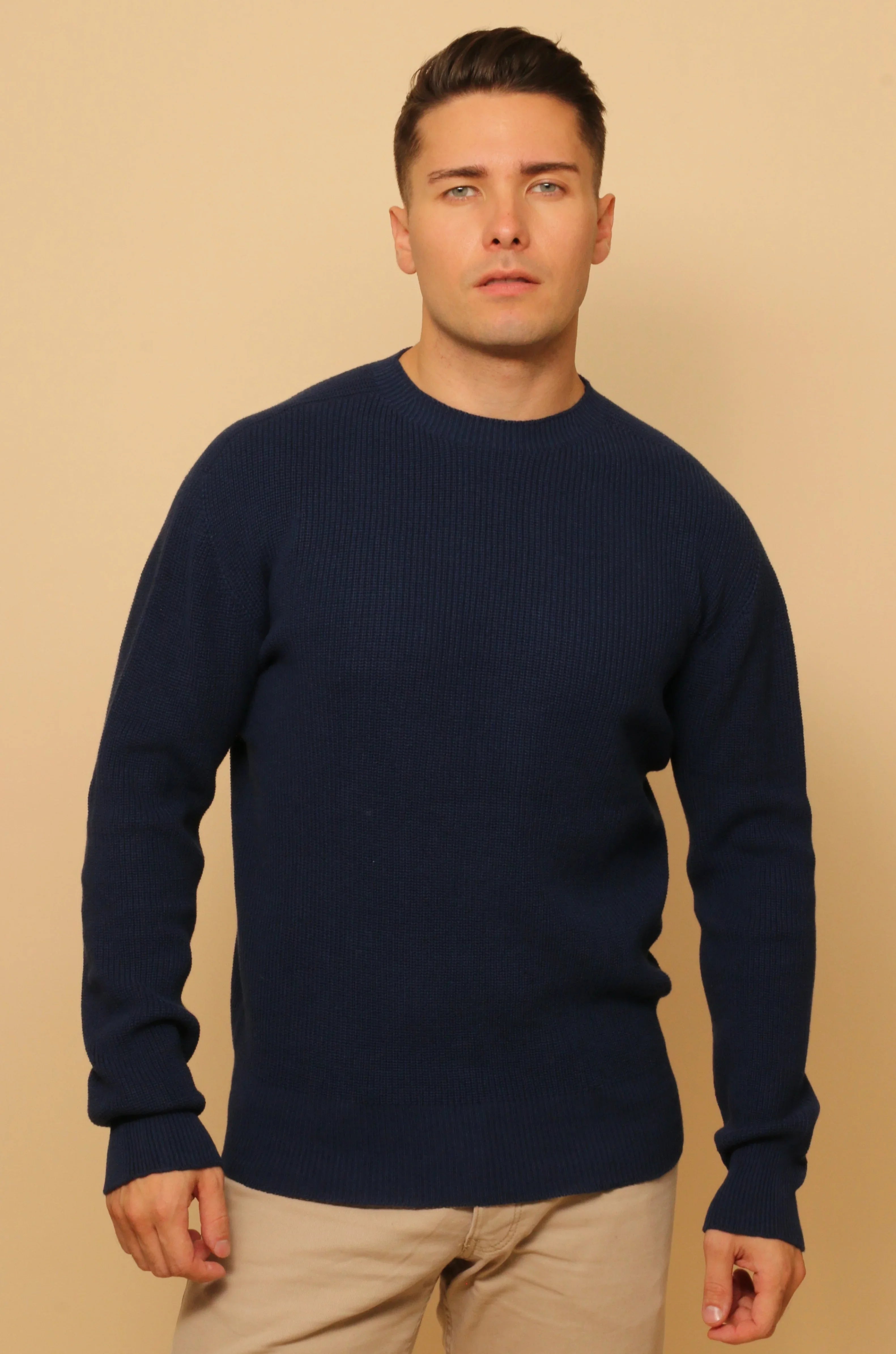 Man wearing a navy blue long-sleeve organic cotton sweater, beige background