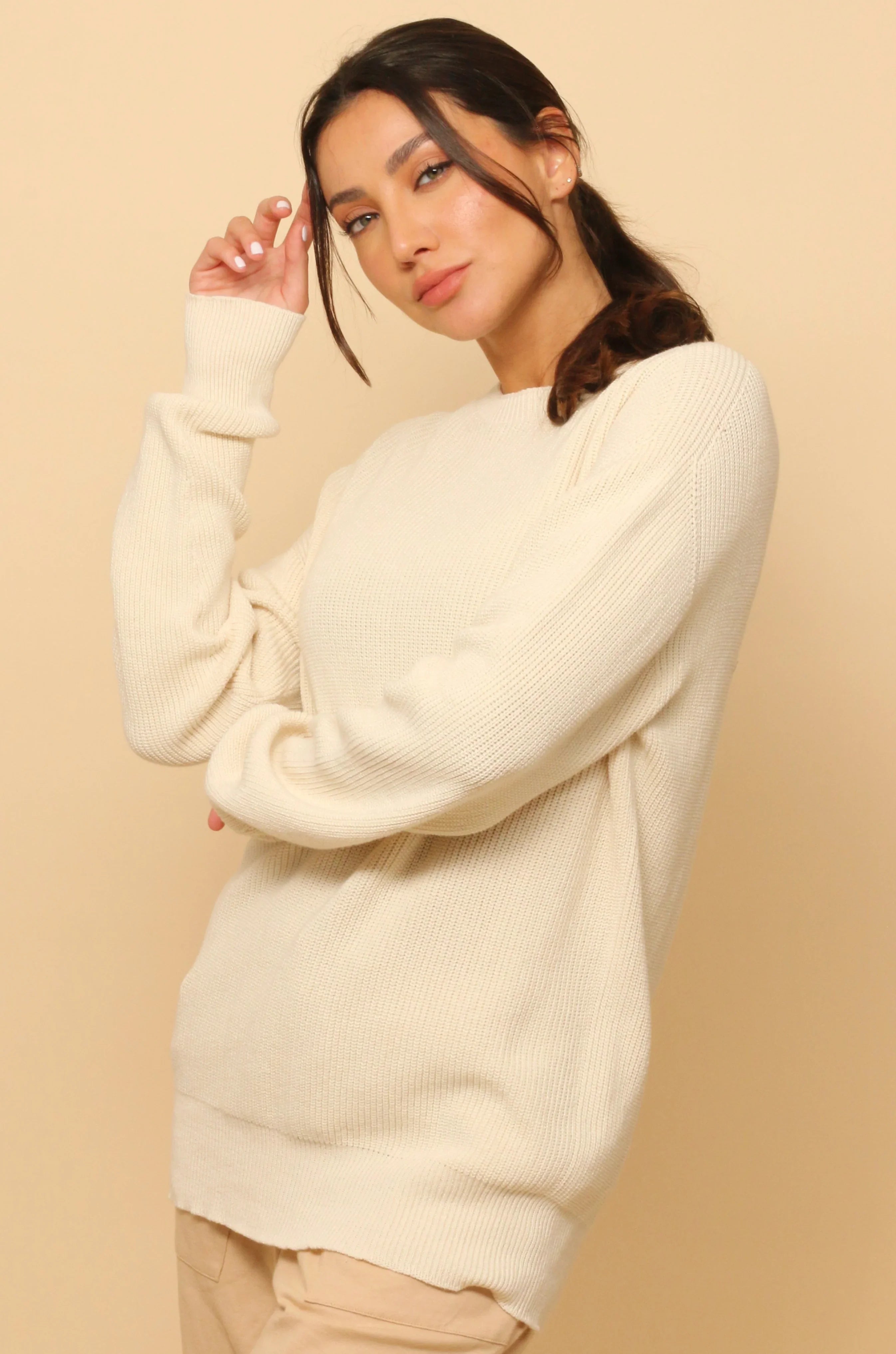 Woman wearing a cream hypoallergenic cotton sweater from Cottonique against beige background